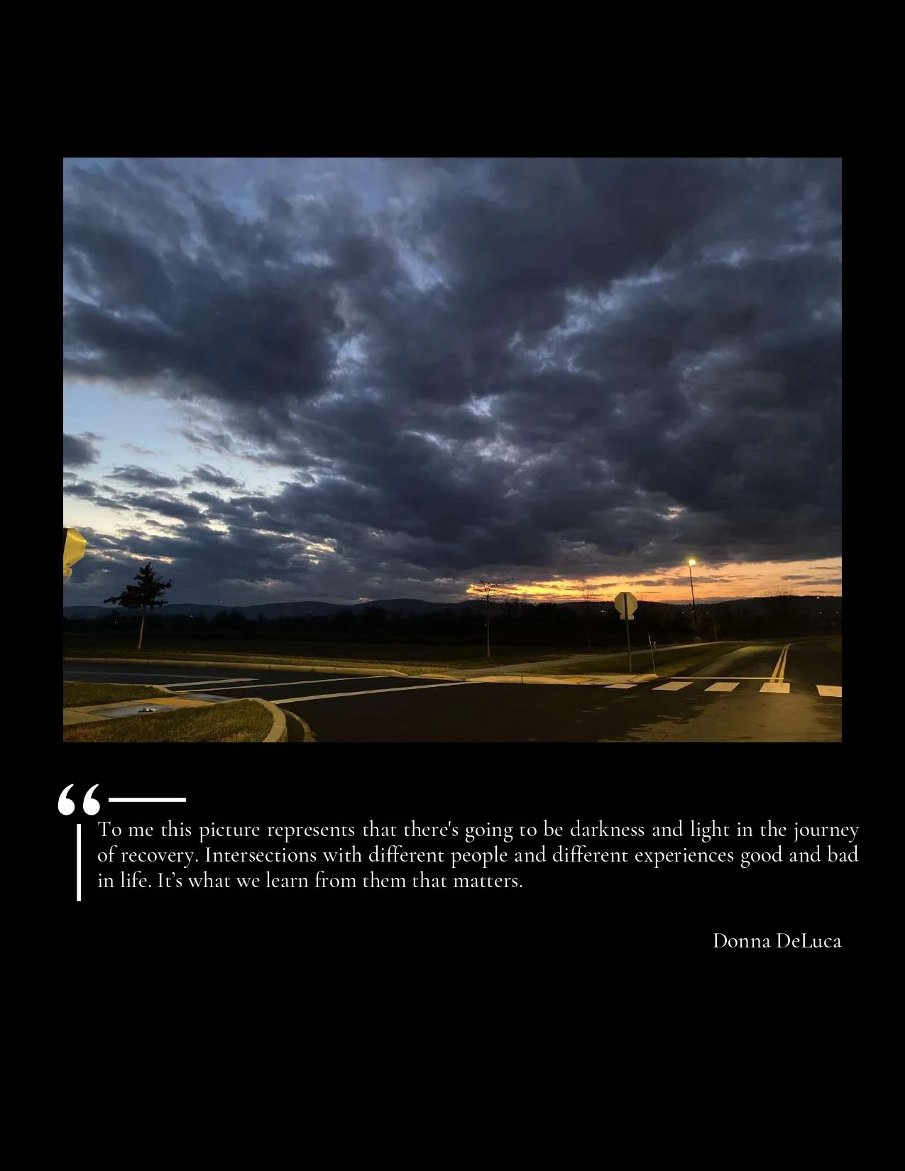 A sunset or sunrise over a dark road with cloudy skies and distant hills.