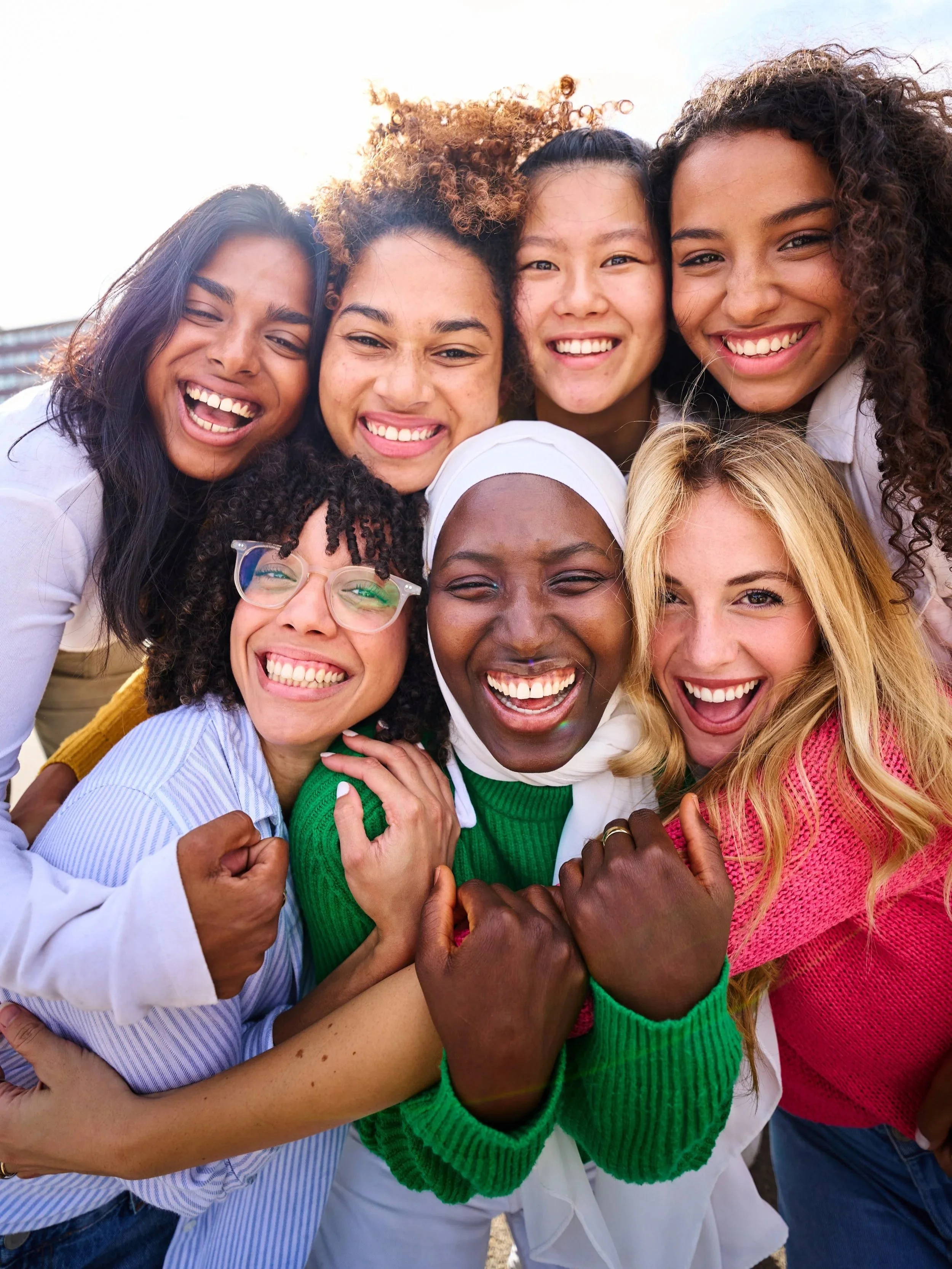 Group of diverse women smiling and showing unity with fists joined