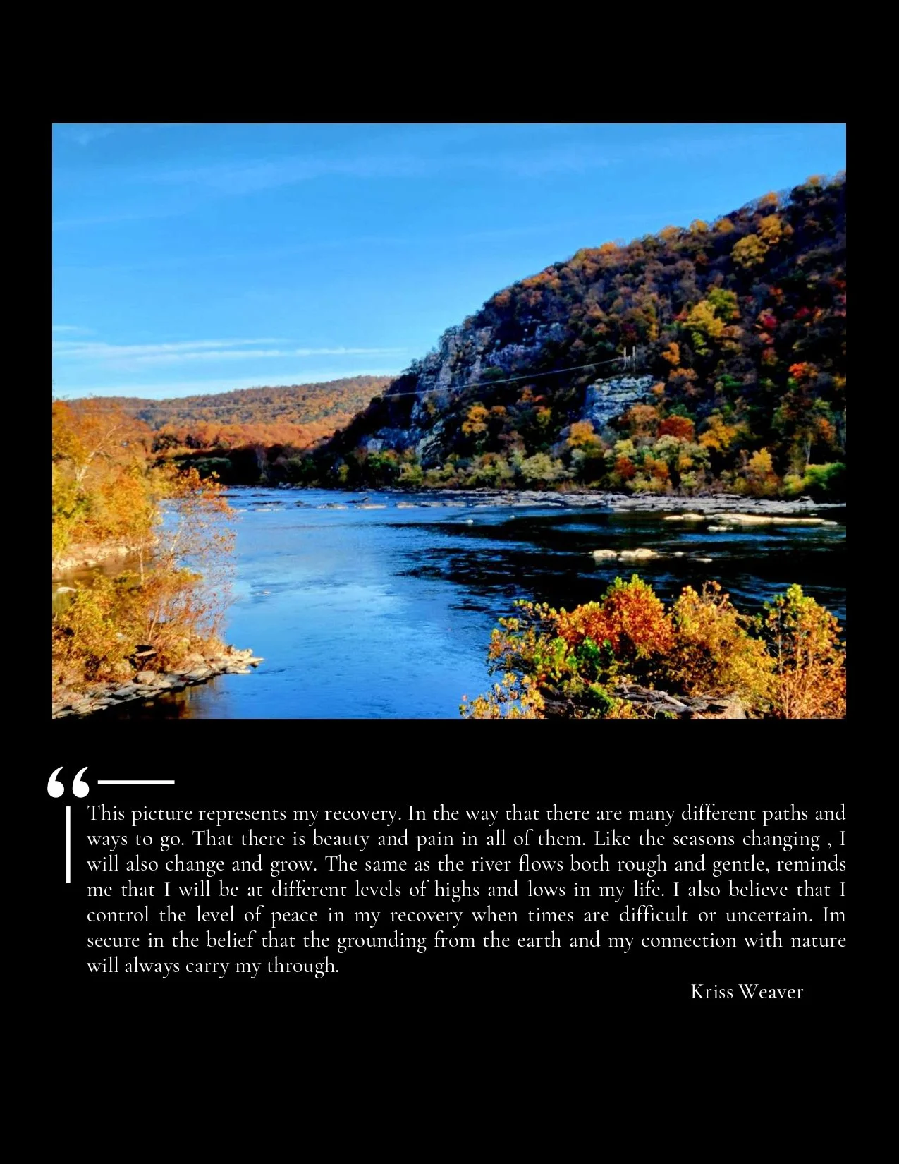 Scenic river landscape with autumn-colored trees on hills, blue sky, and calm water.