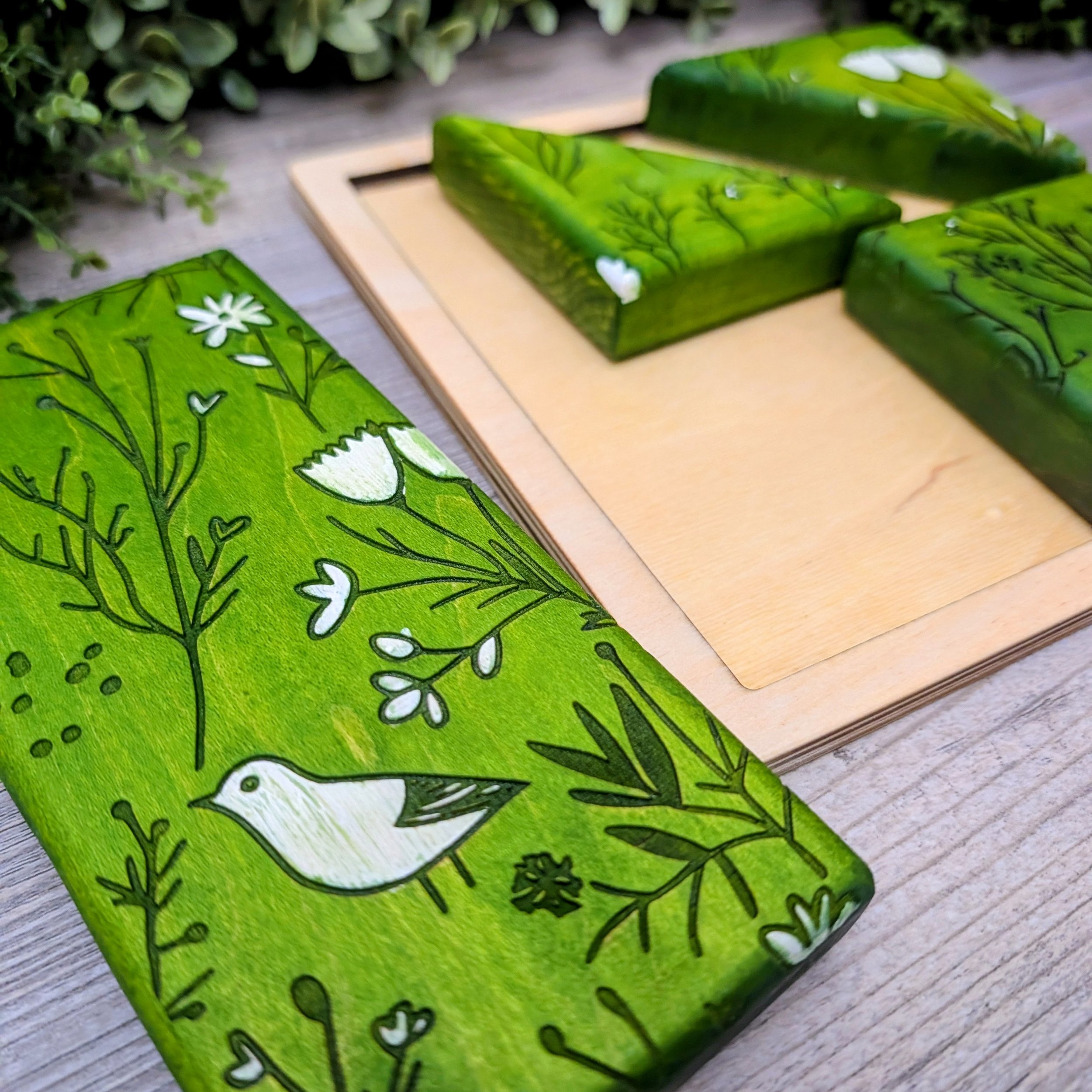 Green and white patterned wooden puzzle featuring bird and floral designs