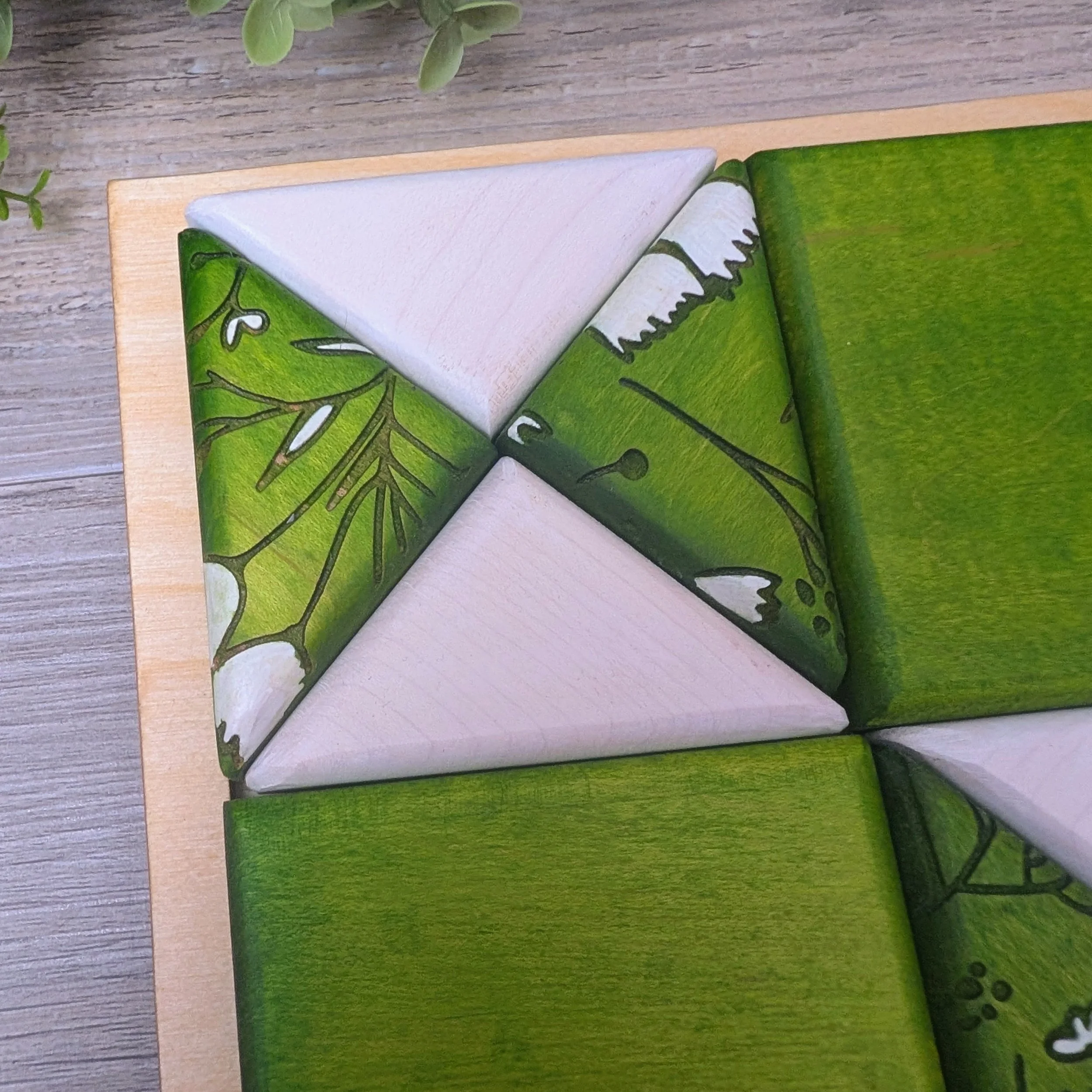 Green and white patterned wooden puzzle featuring bird and floral designs