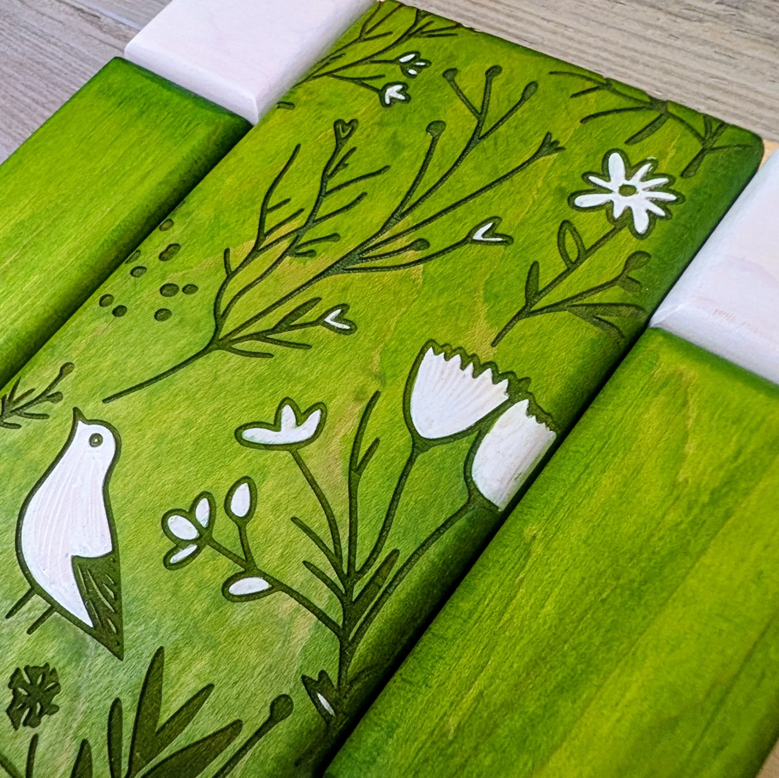Green and white patterned wooden puzzle featuring bird and floral designs