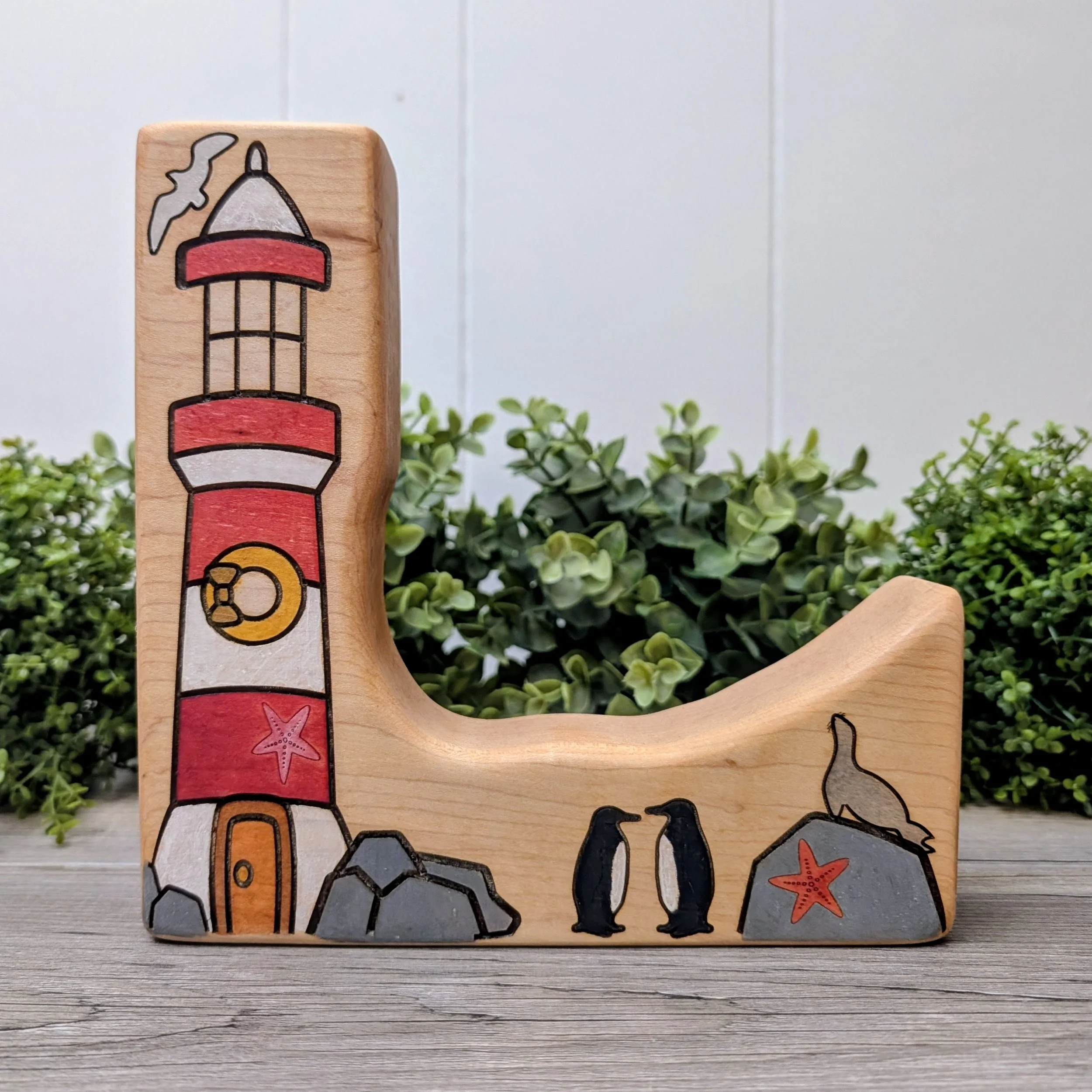 Hand painted wooden lighthouse with red and white stripes and stone base
