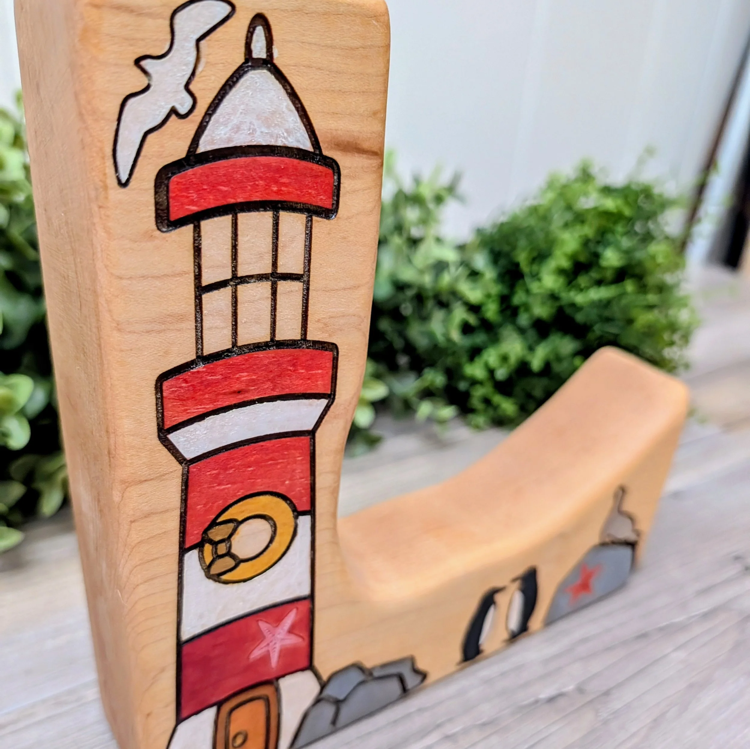 Wooden lighthouse play scene with two penguins and a seal on a rock