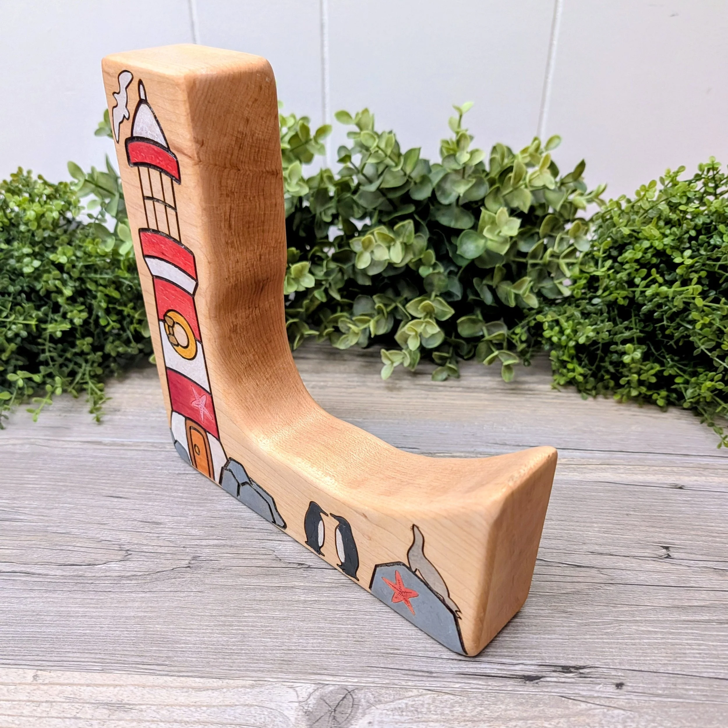 Wooden lighthouse play scene with two penguins and a seal on a rock