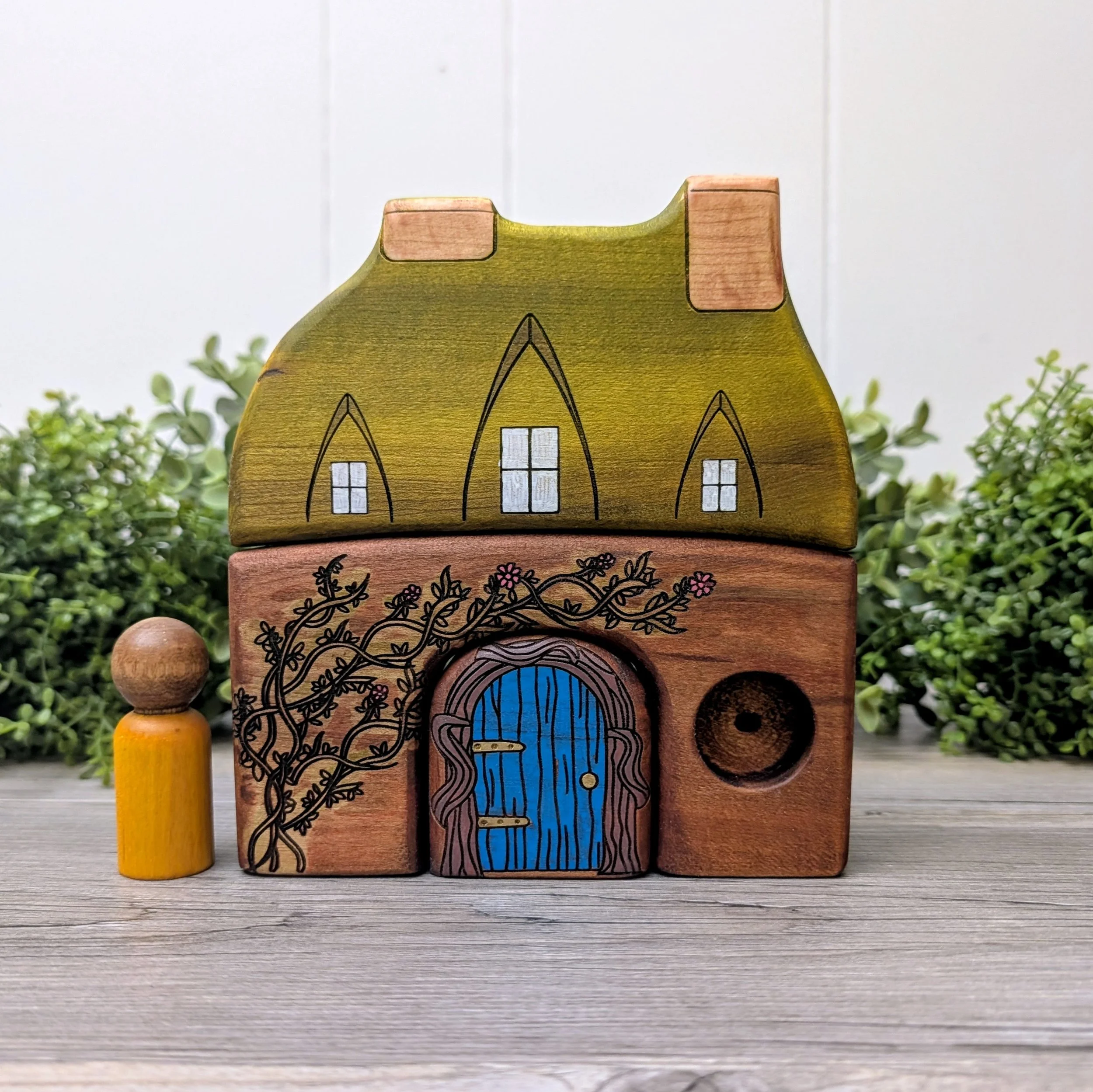 Wooden storybook house featuring vines and partially drilled window