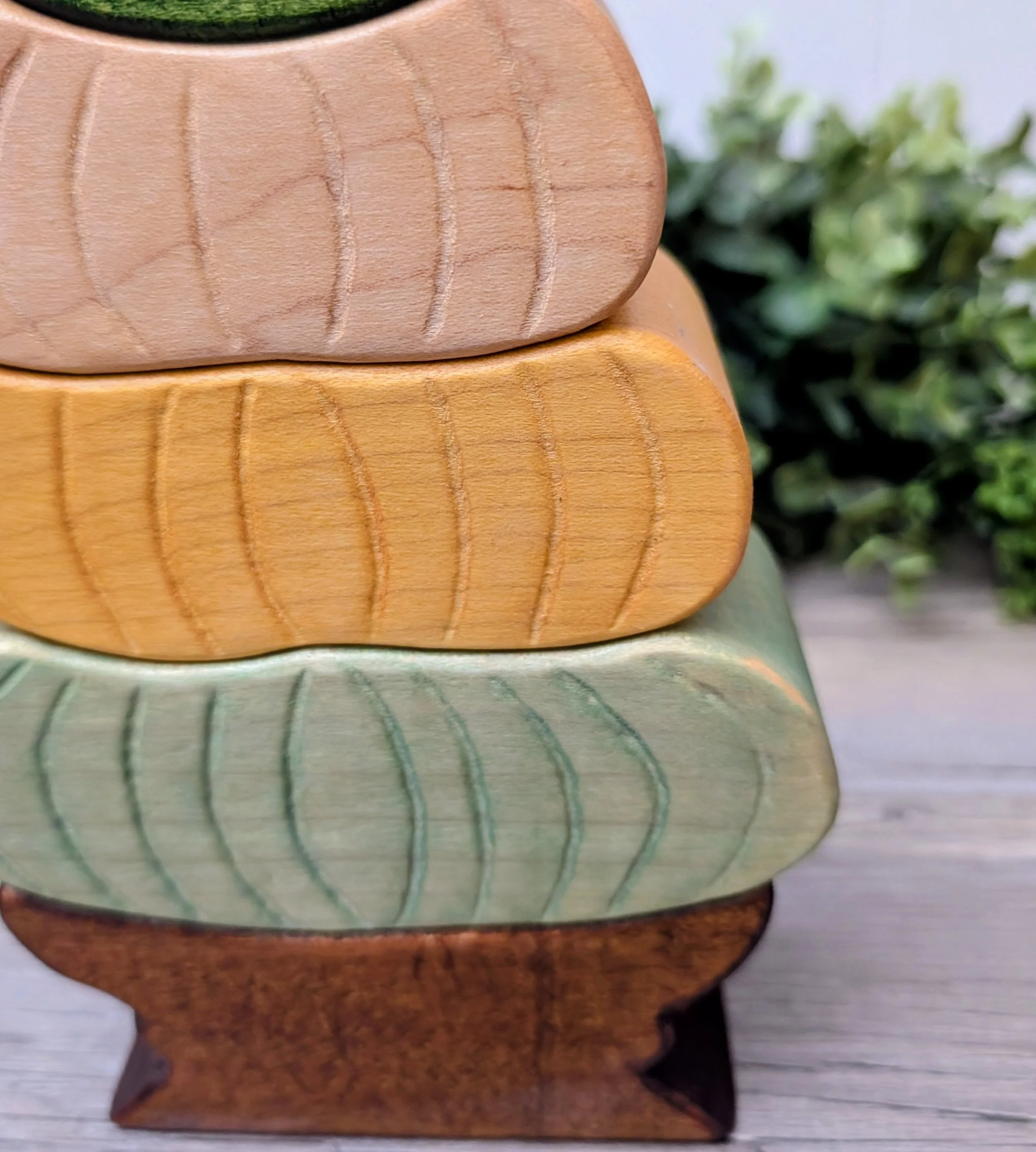 Pastel wooden pumpkins stacked on a brown base with a pumpkin topper