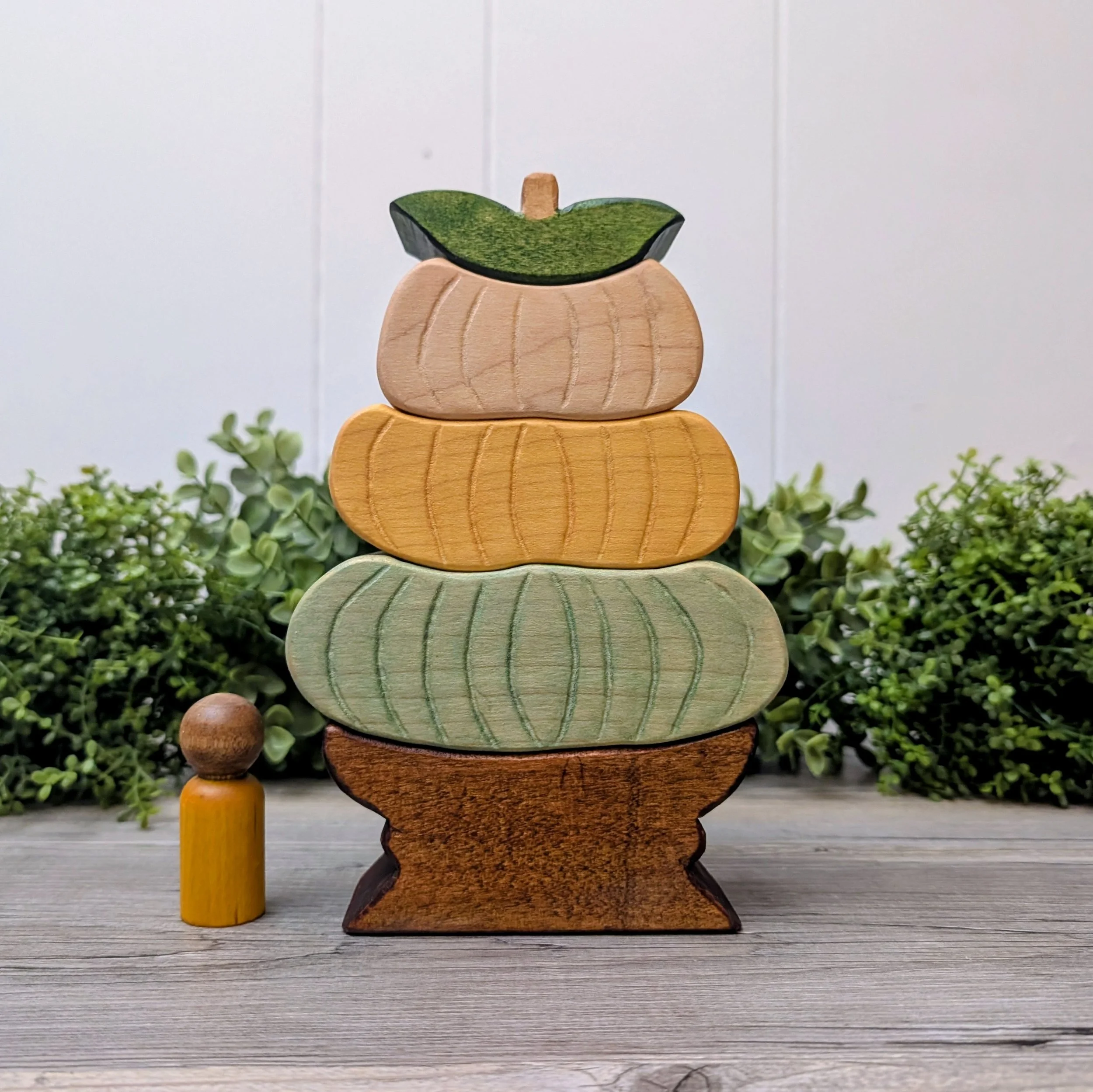Pastel wooden pumpkins stacked on a brown base with a pumpkin topper