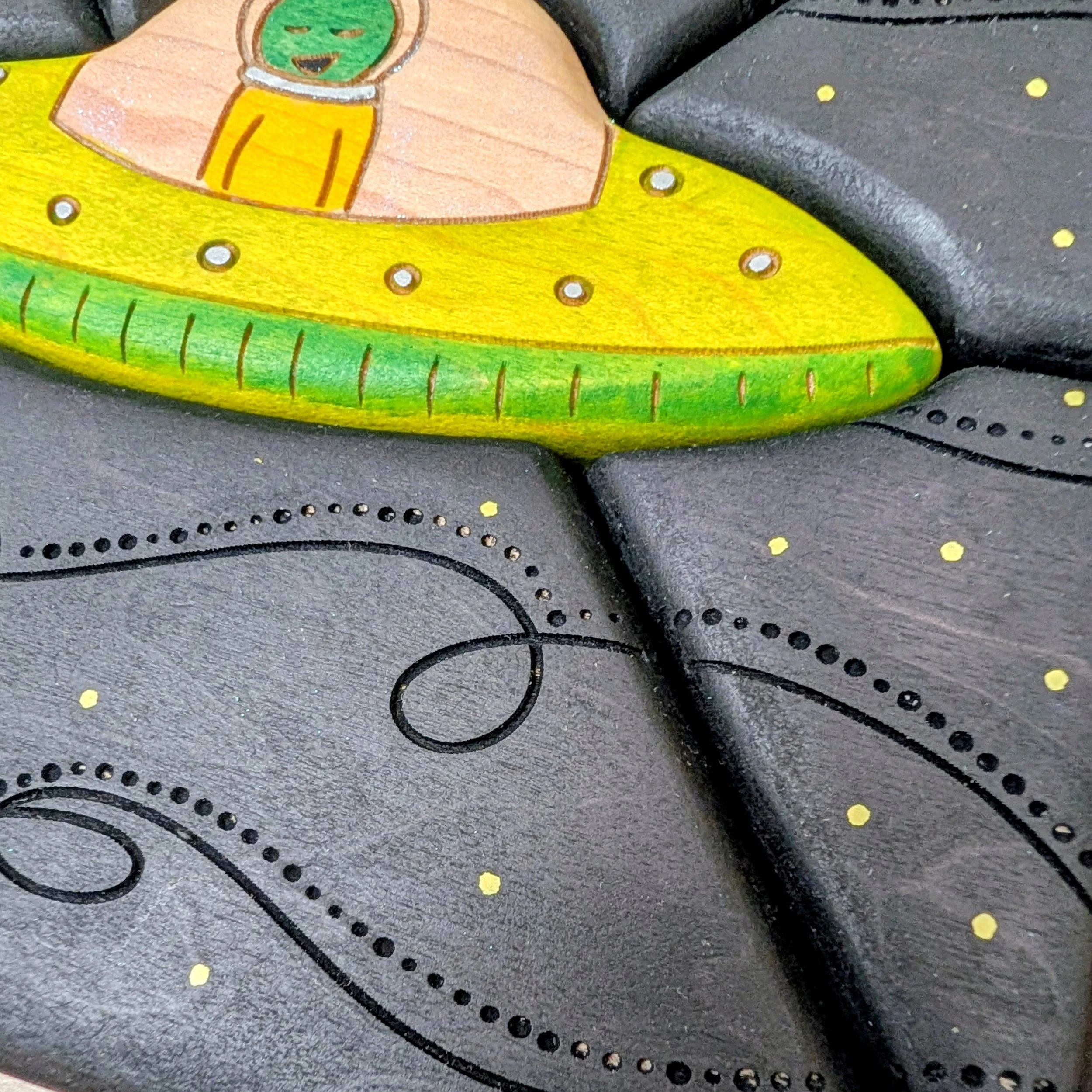 Black wooden puzzle pieces with laser etched space swirls and yellow stars