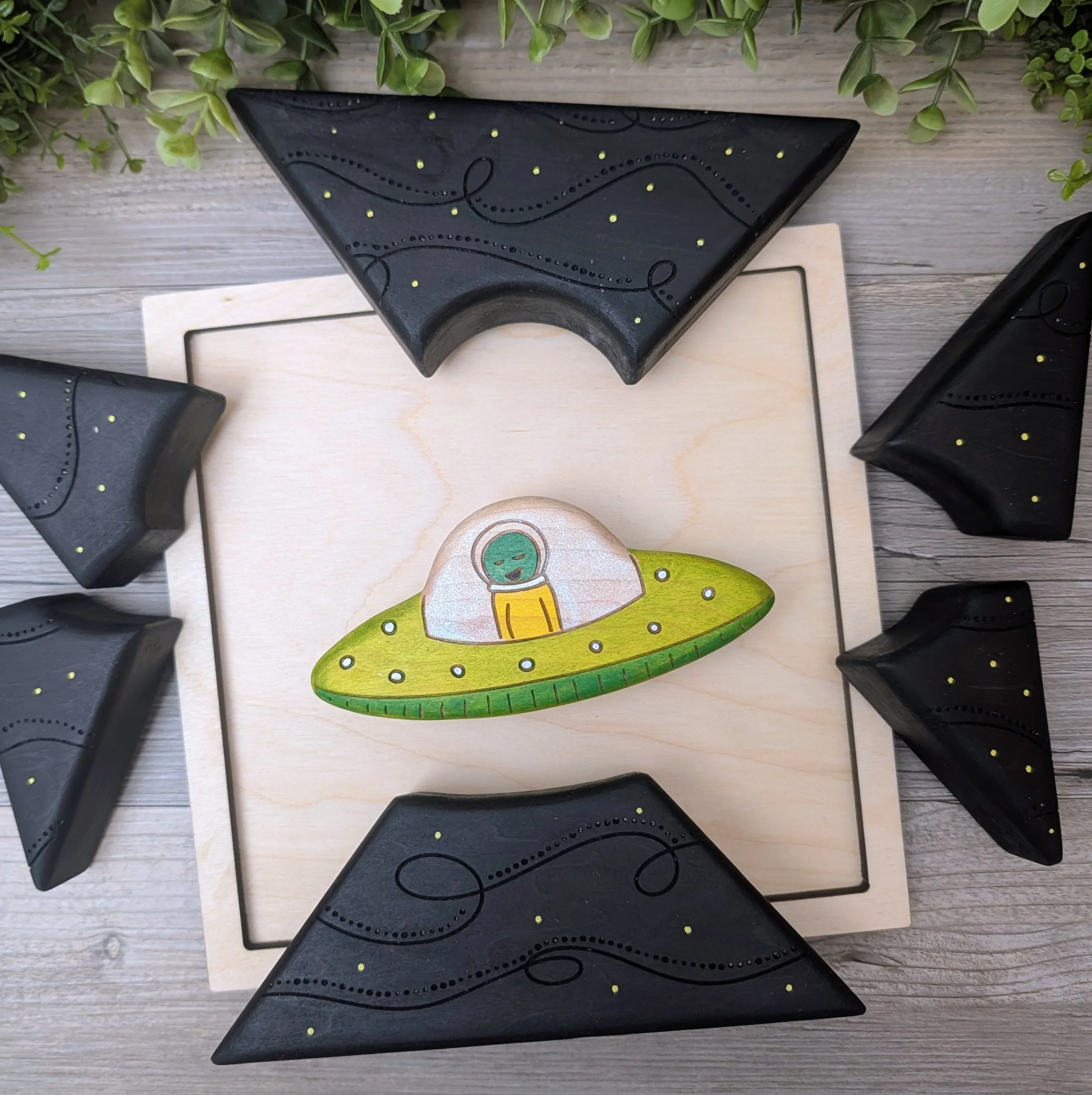 Black wooden puzzle pieces with laser etched space swirls and yellow stars