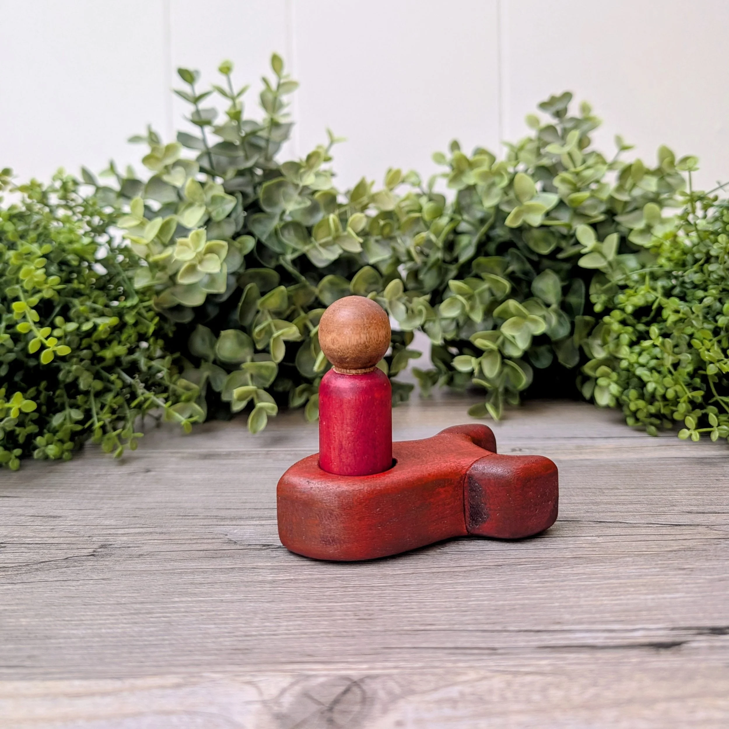 Maple peg person seated inside wooden rocket ship