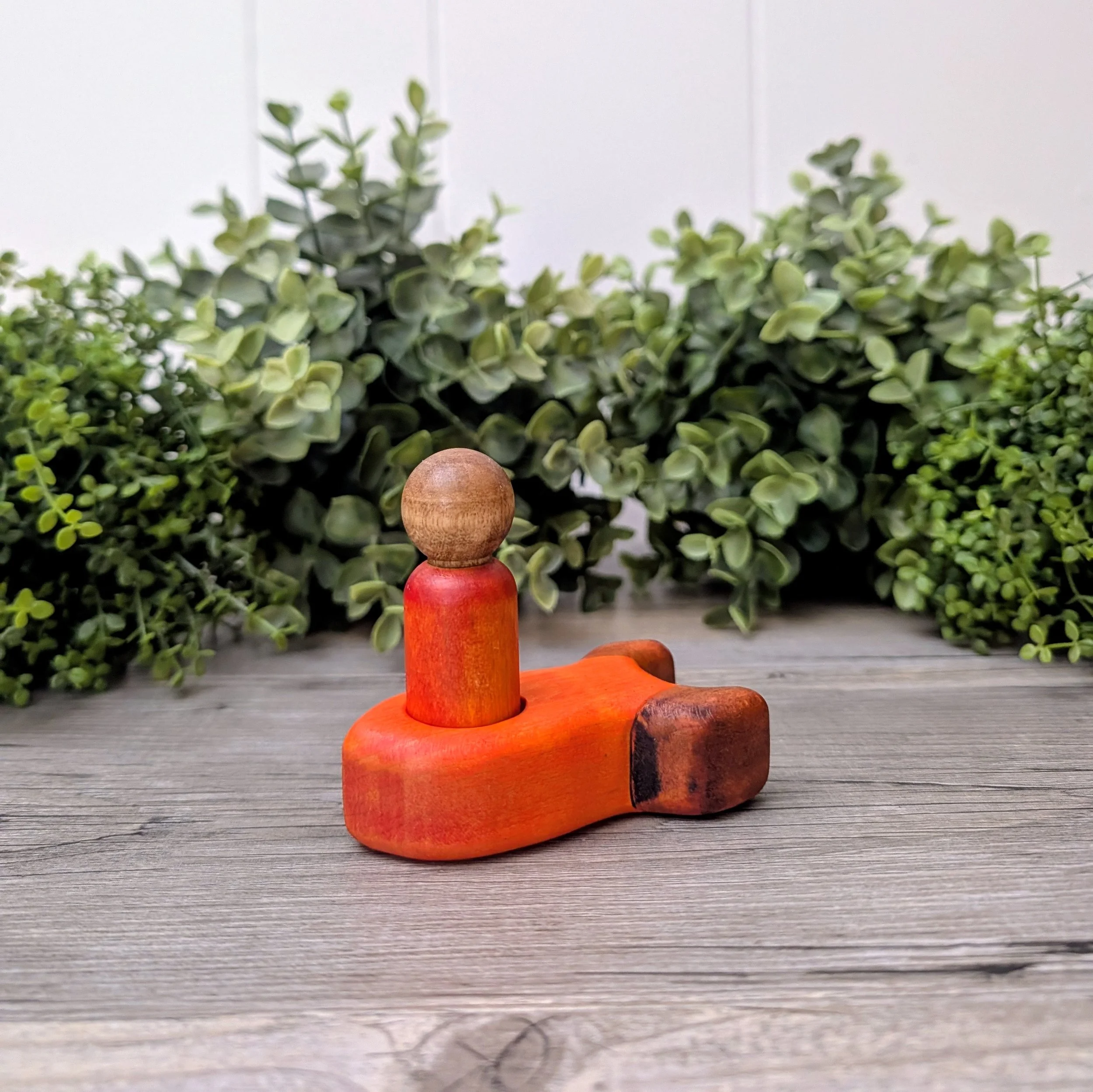 Maple peg person seated inside wooden rocket ship