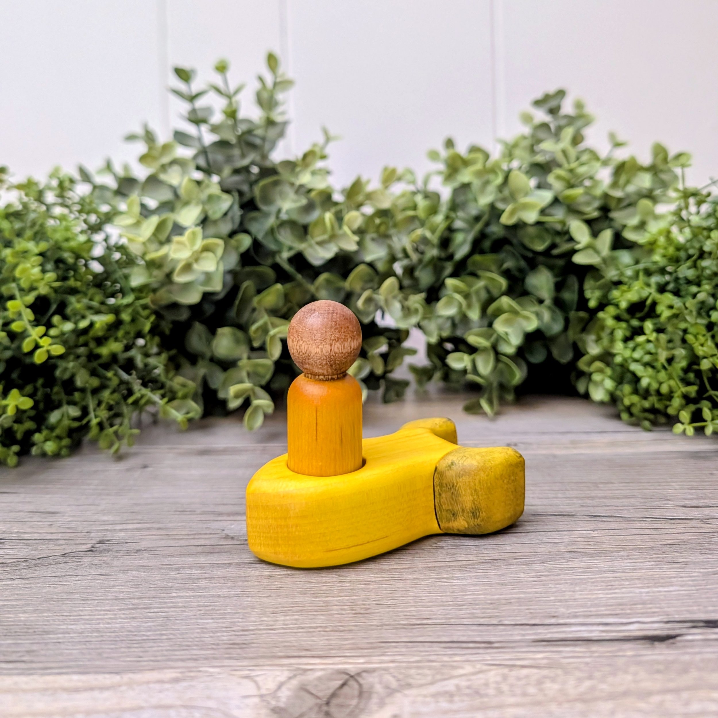 Maple peg person seated inside wooden rocket ship