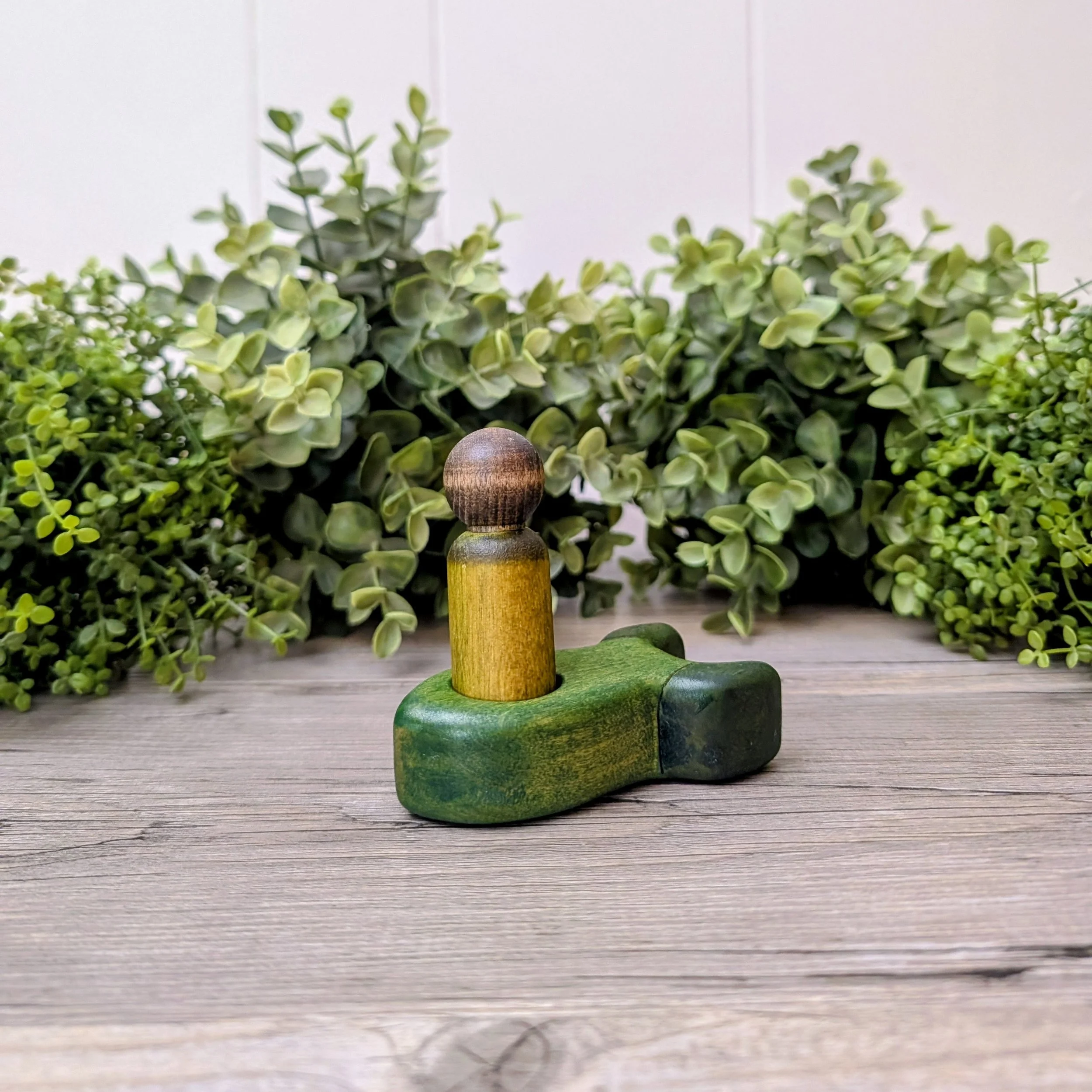 Maple peg person seated inside wooden rocket ship