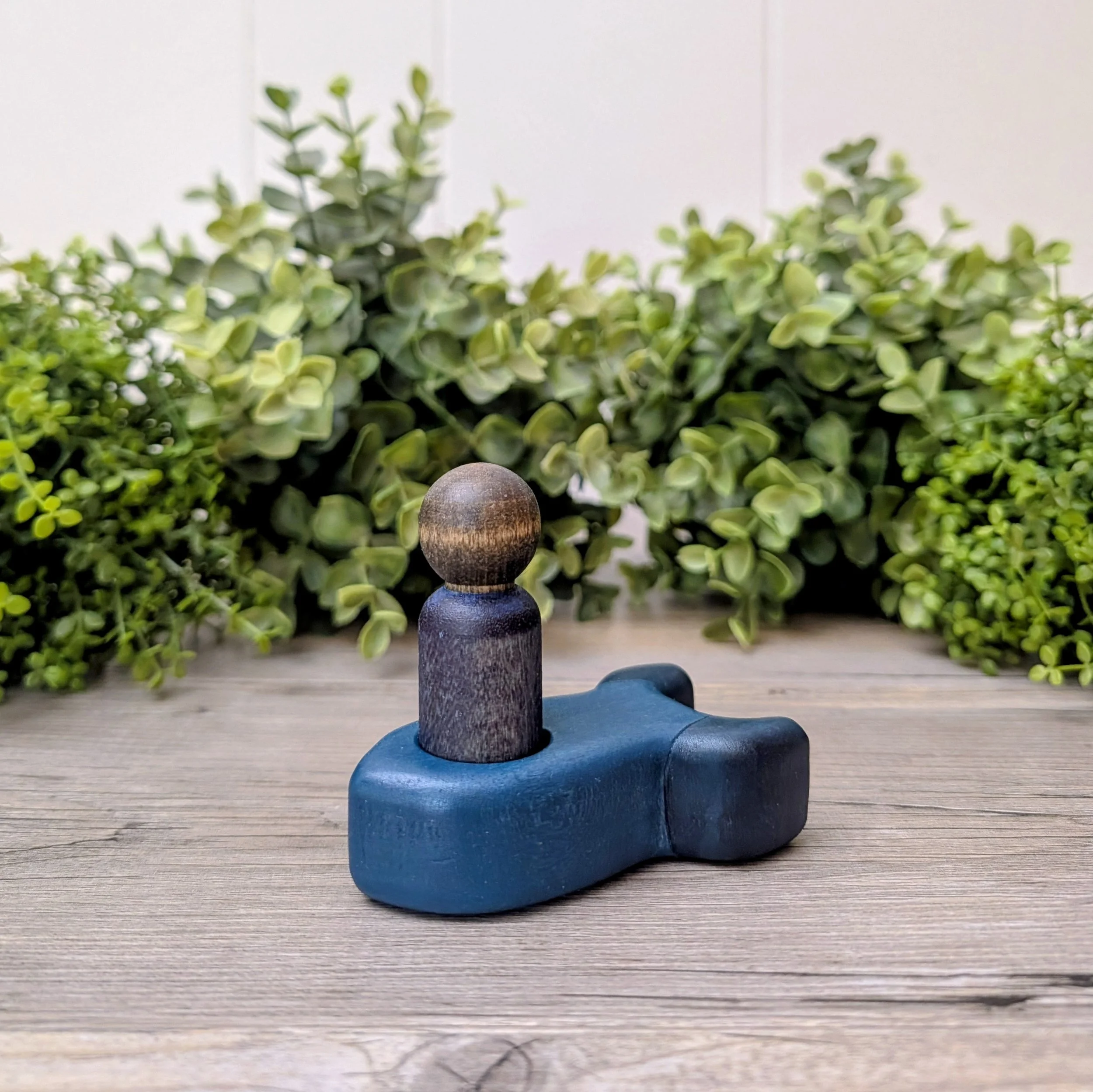 Maple peg person seated inside wooden rocket ship