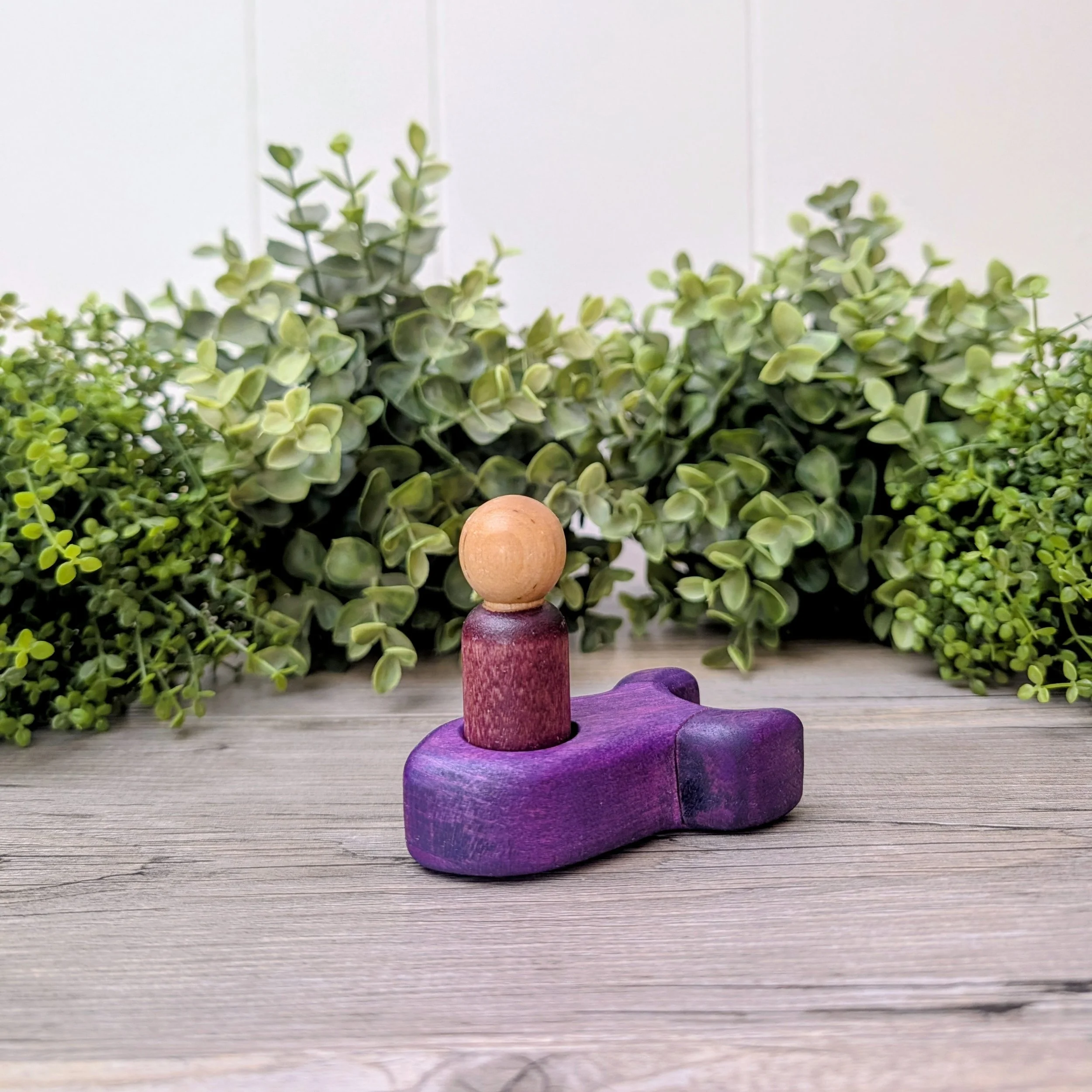 Maple peg person seated inside wooden rocket ship