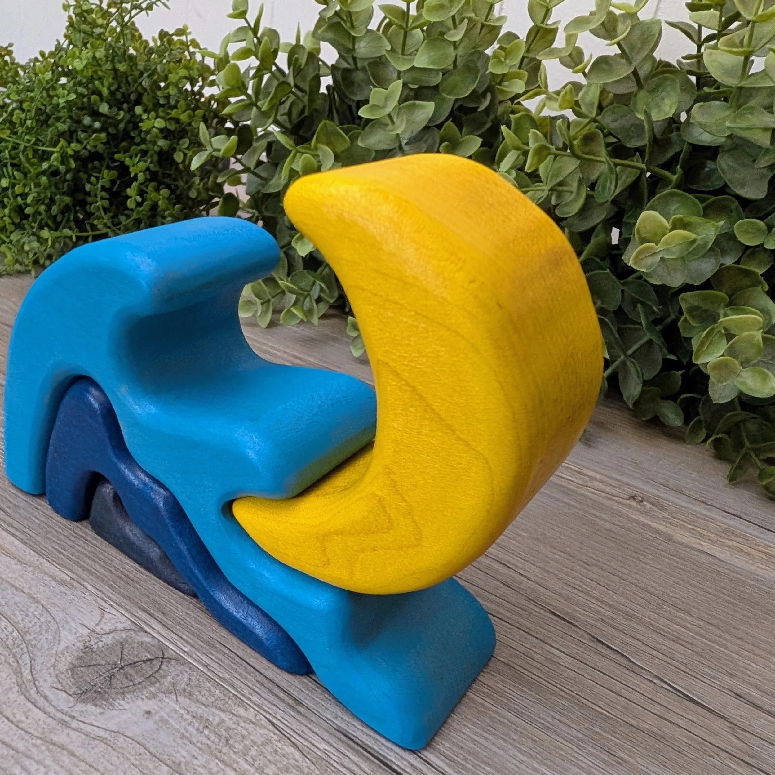 Yellow moon fitting inside curved wooden wave piece