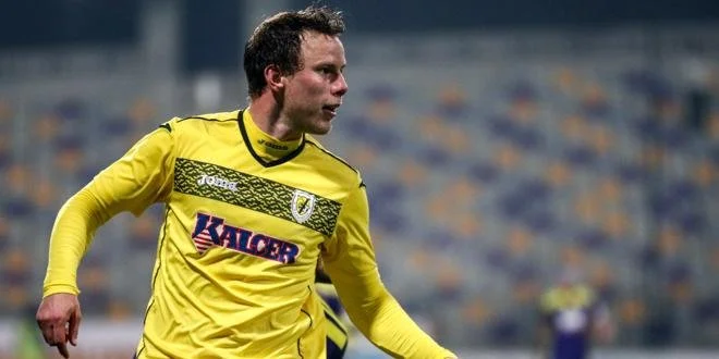 A soccer player in a yellow jersey on a field during a game.
