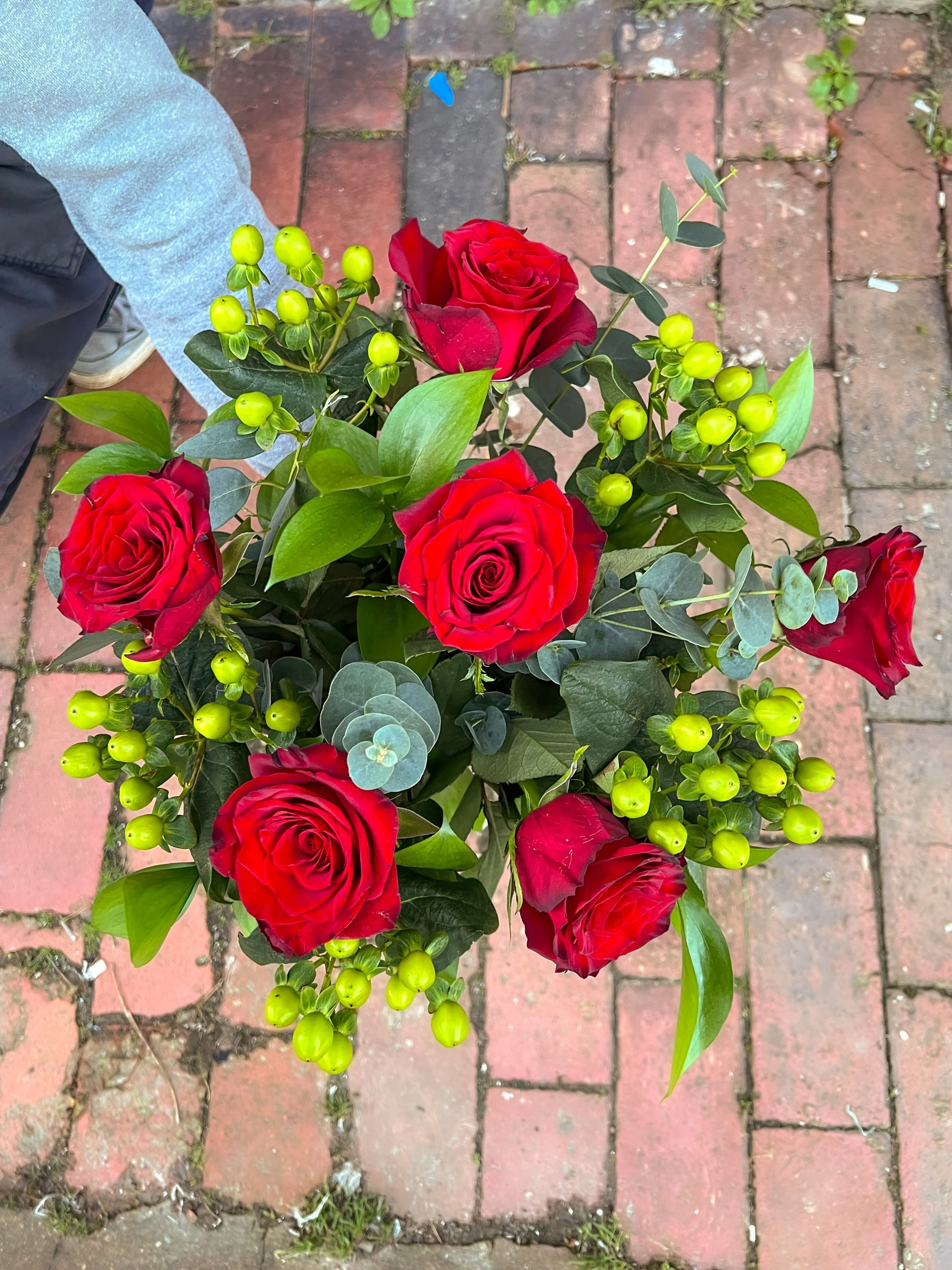 Luxury red roses, foliage and glossy green hypericum berries.