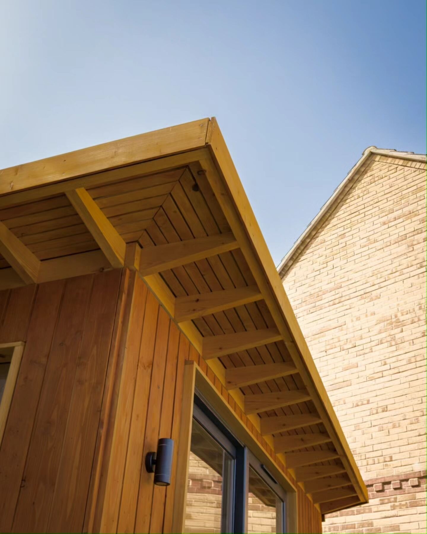 Our overhanging eaves protect the doorway from rain in the winter, whilst adding shade in the summer.

We also love the drama they add to the silhouette.

We used locally-grown British Larch for the cladding and detailing, and Scandinavian redwood fo