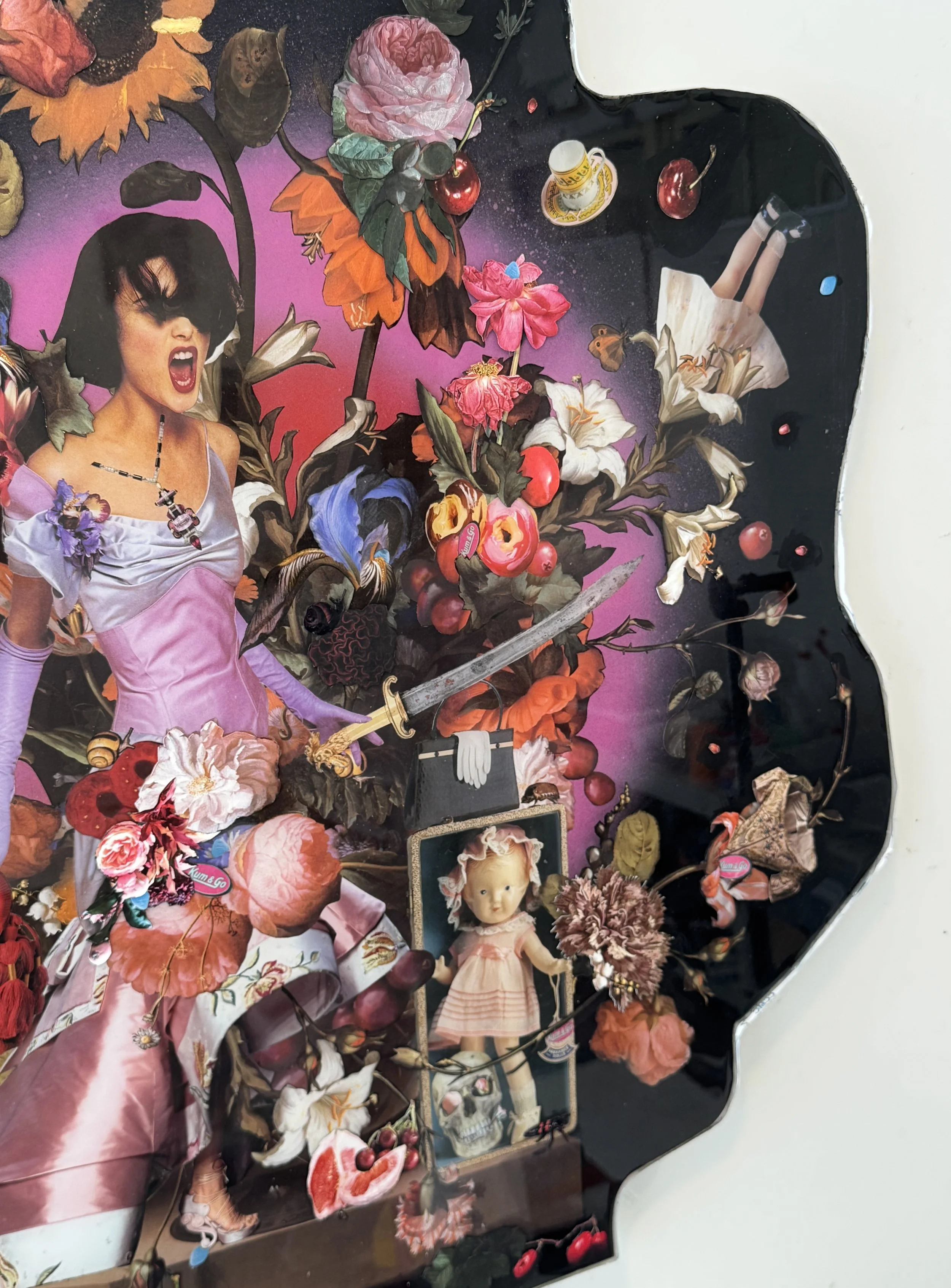 A collage with various flowers, cherries, a doll, a knife, a small coffee cup, a picture frame, and a woman in a pink dress with dark hair.