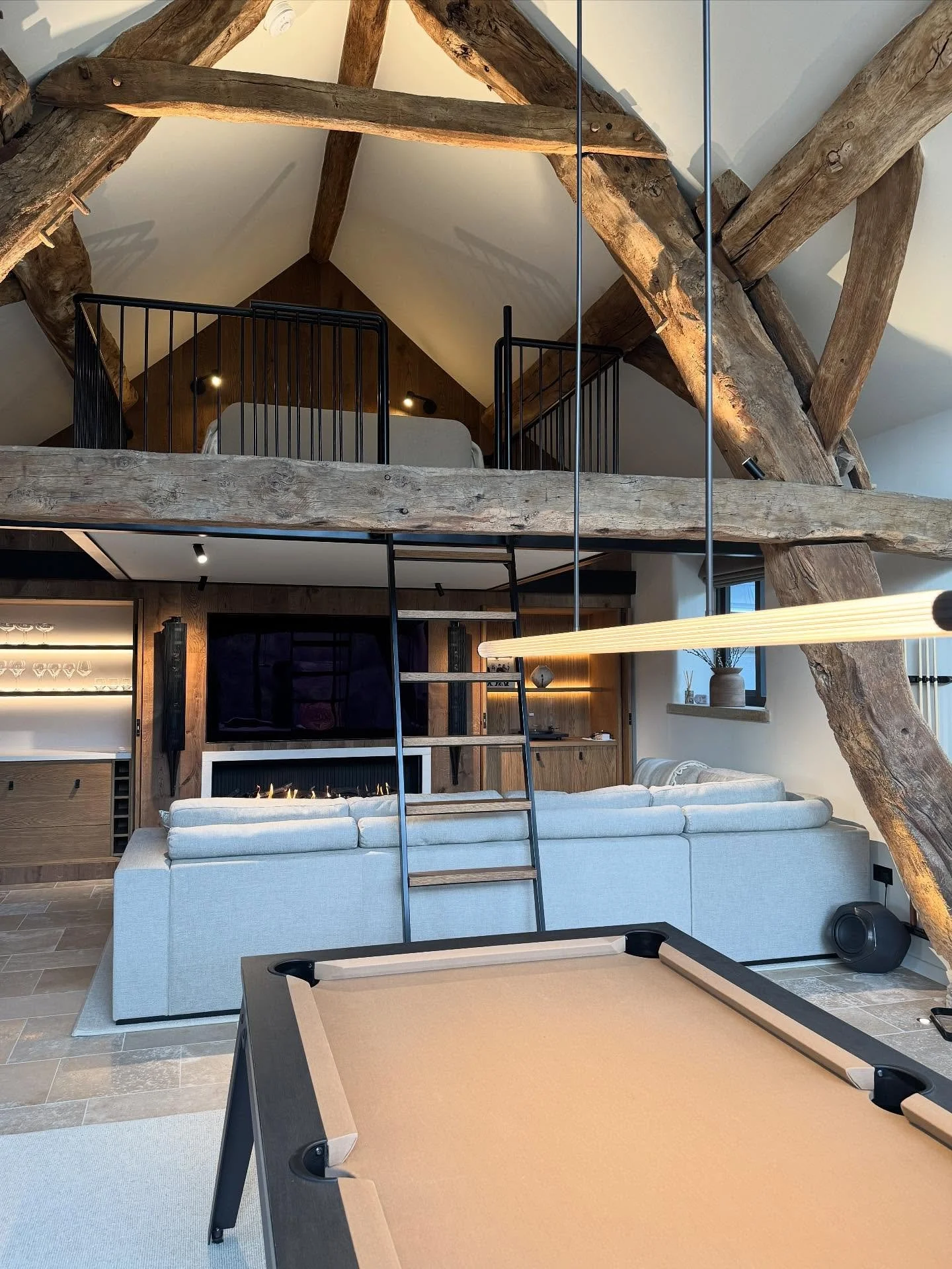 ✨Our clients beautiful Grade II listed barn had exposed stone and timeworn beams which we reimagined into a contemporary entertainment space✨
Now with a cosy fireside lounge, a mezzanine sleeping loft, bespoke games area and a sleek kitchenette, this