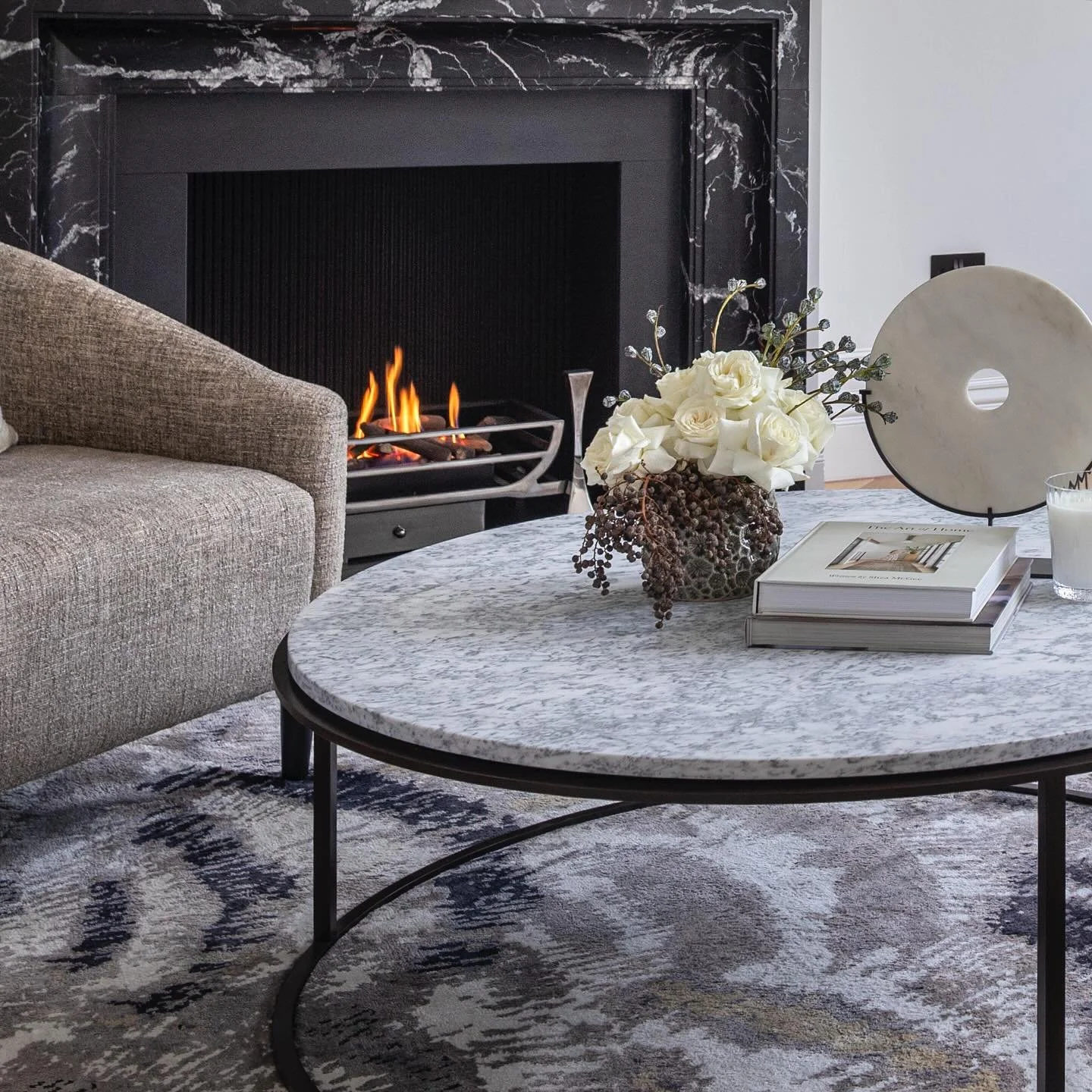 ✨The heart of this room is the stunning fireplace, framed in striking Nero Marquina, an architectural surround that anchors the space, adding drama. We designed the seating to draw you in close: sculptural armchairs positioned for conversation, warmt