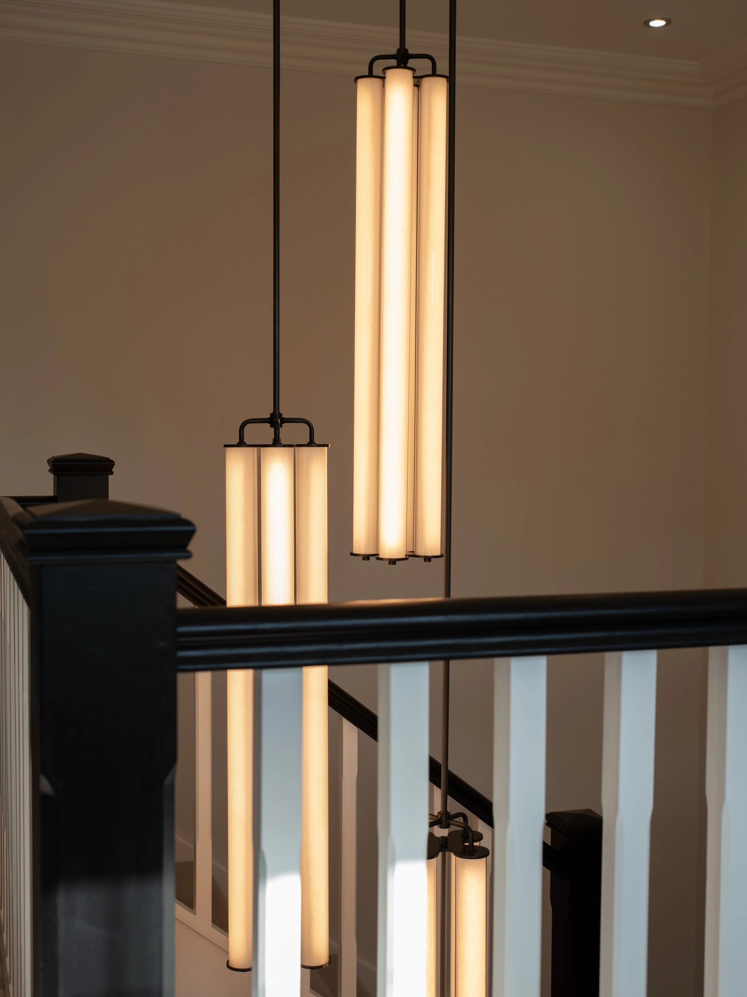 A hallway should do more than simply connect spaces, it should create a memorable first impression.
For this new-build home, there was no natural focal point within the stairwell, so with the team @fritz_fryer_lighting we designed a bespoke arrangeme