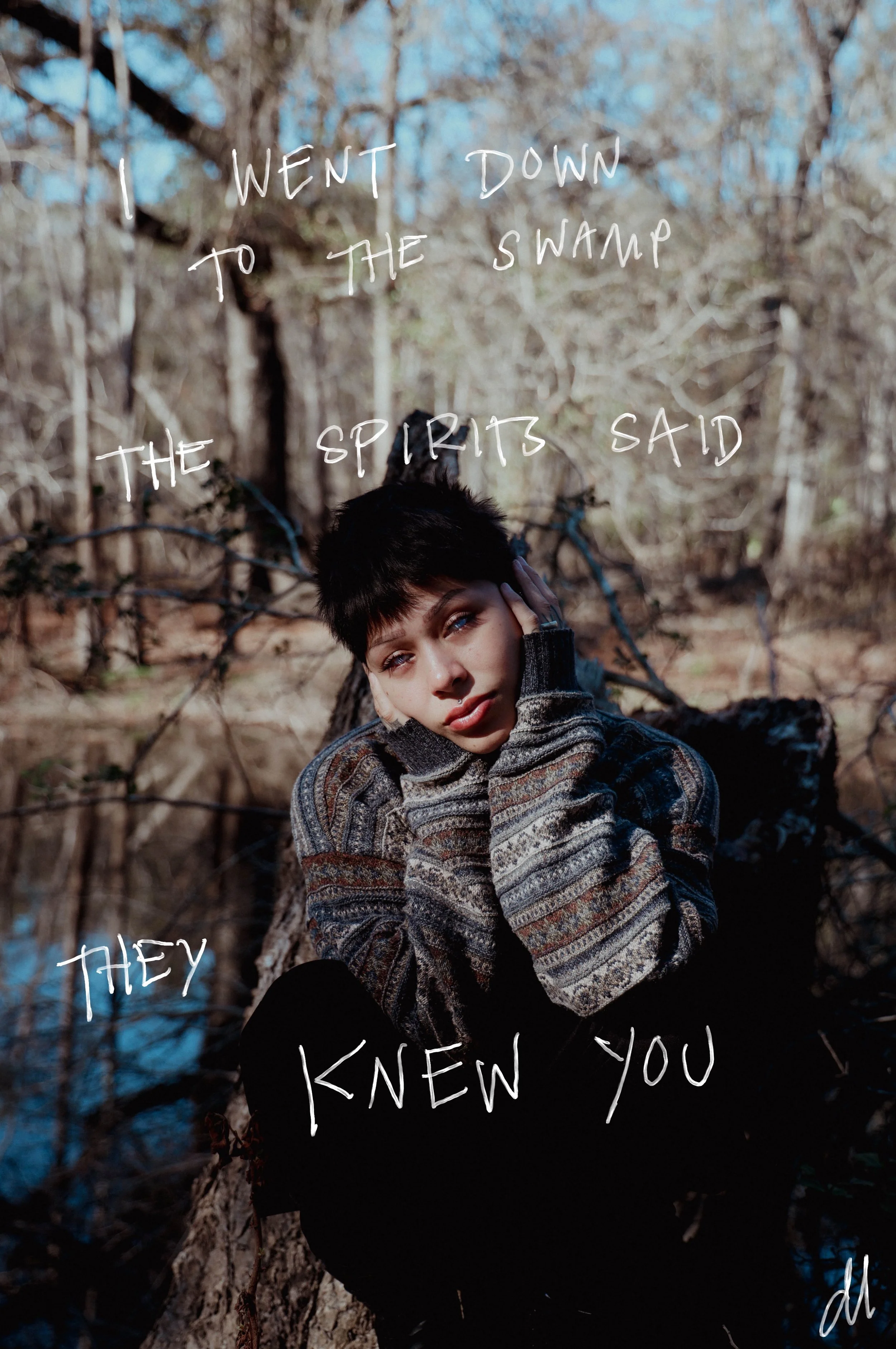 Portrait of a young woman with short dark hair sitting outdoors on a fallen tree in a wooded area, wearing a patterned sweater, with handwritten-style text overlay reading 'I went down to the swamp the spirits said they knew you'.