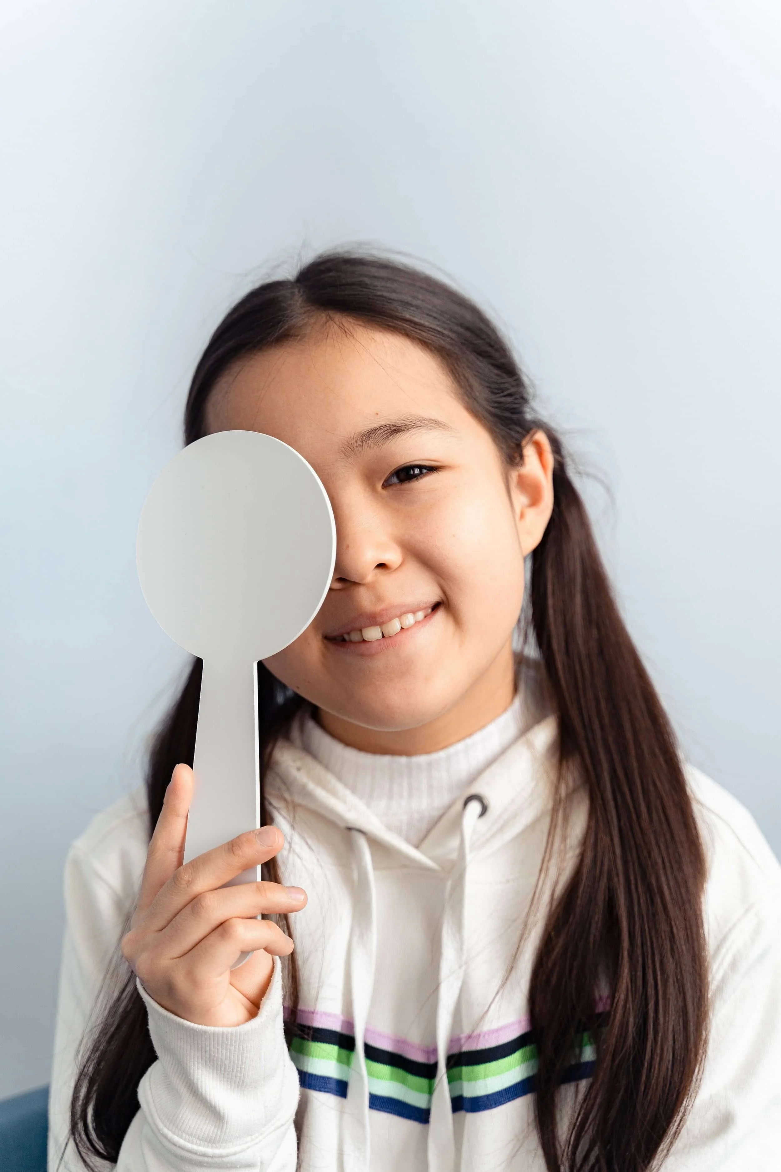 Young girl covering one eye to test her vision