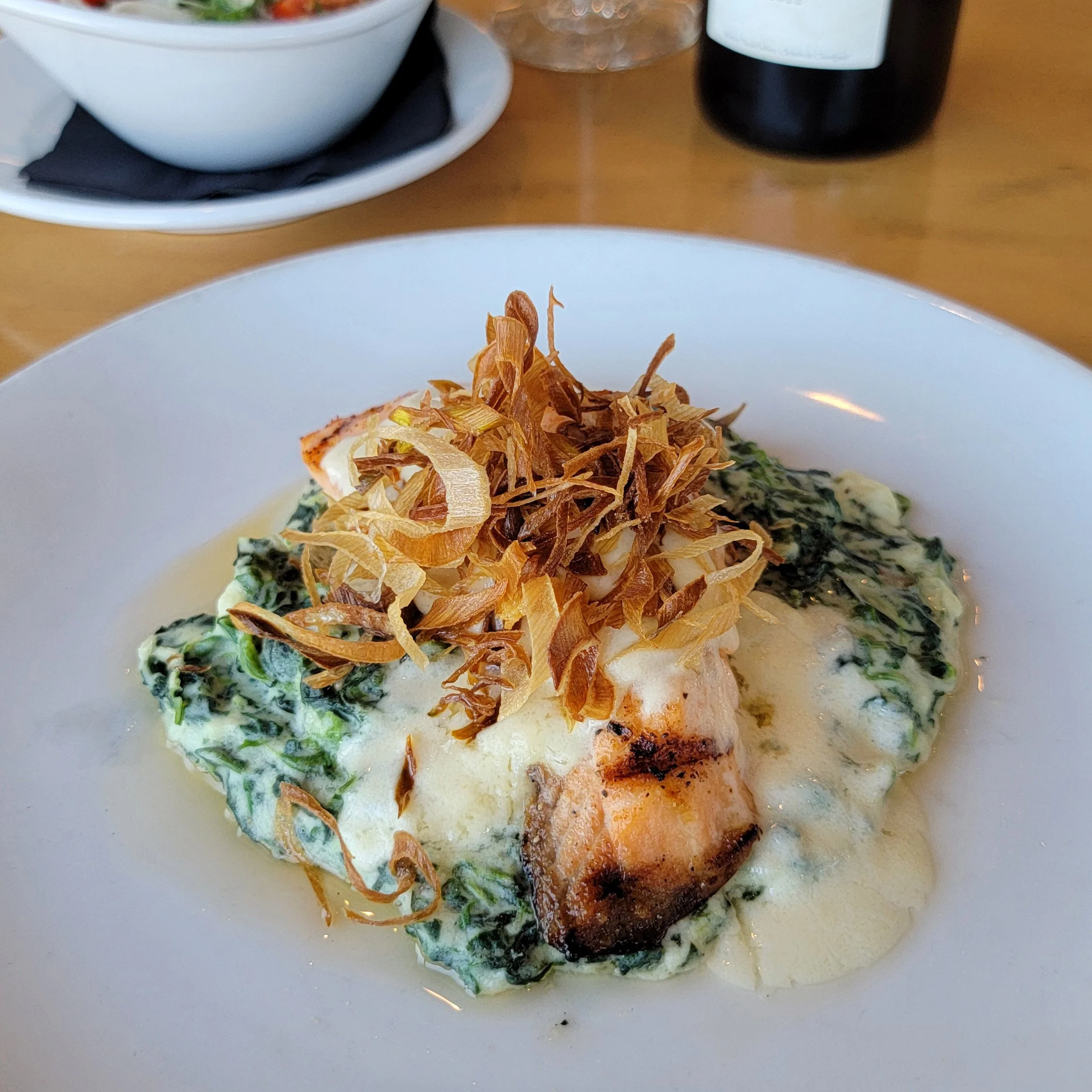 Salmon and creamed spinach with crispy fried onions.  to a perfectly grilled salmon filet. Fresh seasonal berries scattered on top with lemon-honey vinaigrette