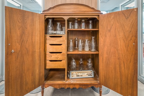 Display cabinet showing old milk bottles that C&amp;C delivered in the late 1800s