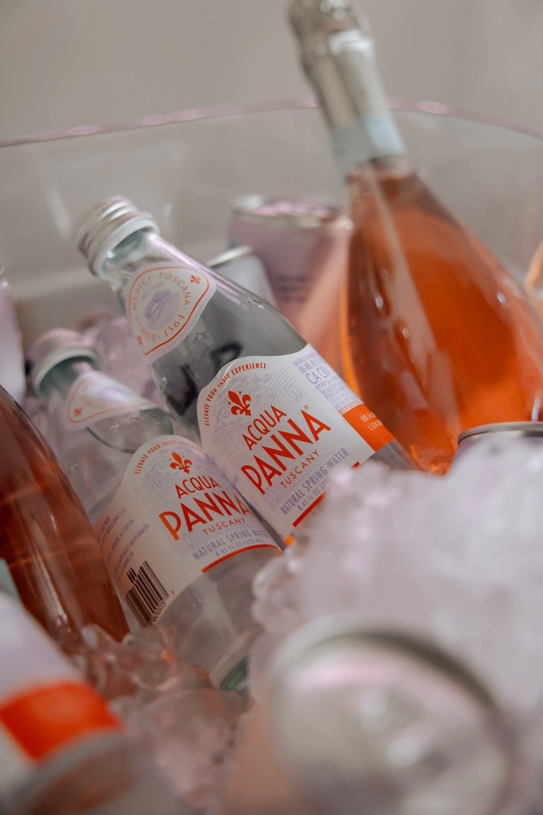 Close-up of bottles of Acqua Panna natural spring water, with some bottles lying on their side and others upright, in a container filled with ice.