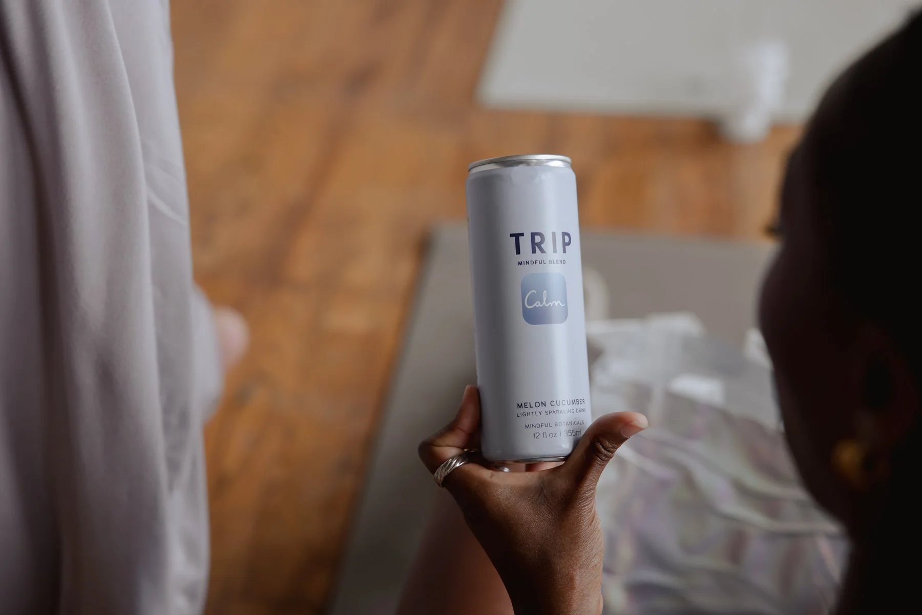 A hand holding a can of TRIP brand sparkling drink labeled 'Calm' with melon cucumber flavor.