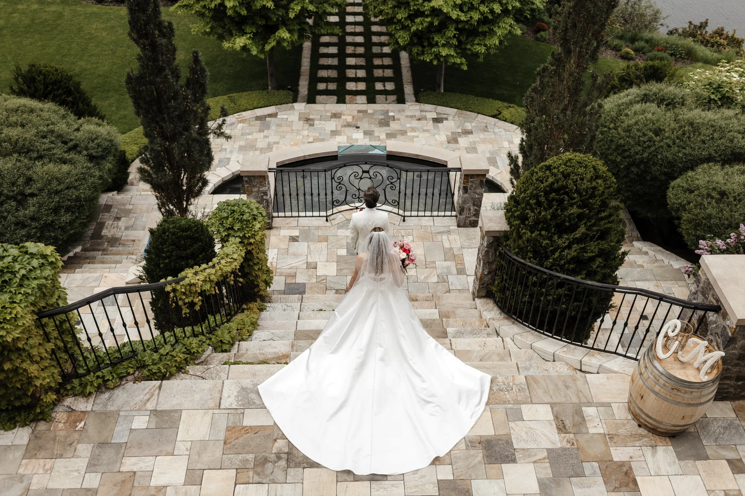 A bride and groom standing on a stone terrace in the Okanagan. The groom is dressed in a light-colored suit and the bride is in a ballgrown. Day by Knight Events is the Wedding Planner. Tara Peach Photography. Venue at Chateau Okanagan in Kelowna BC