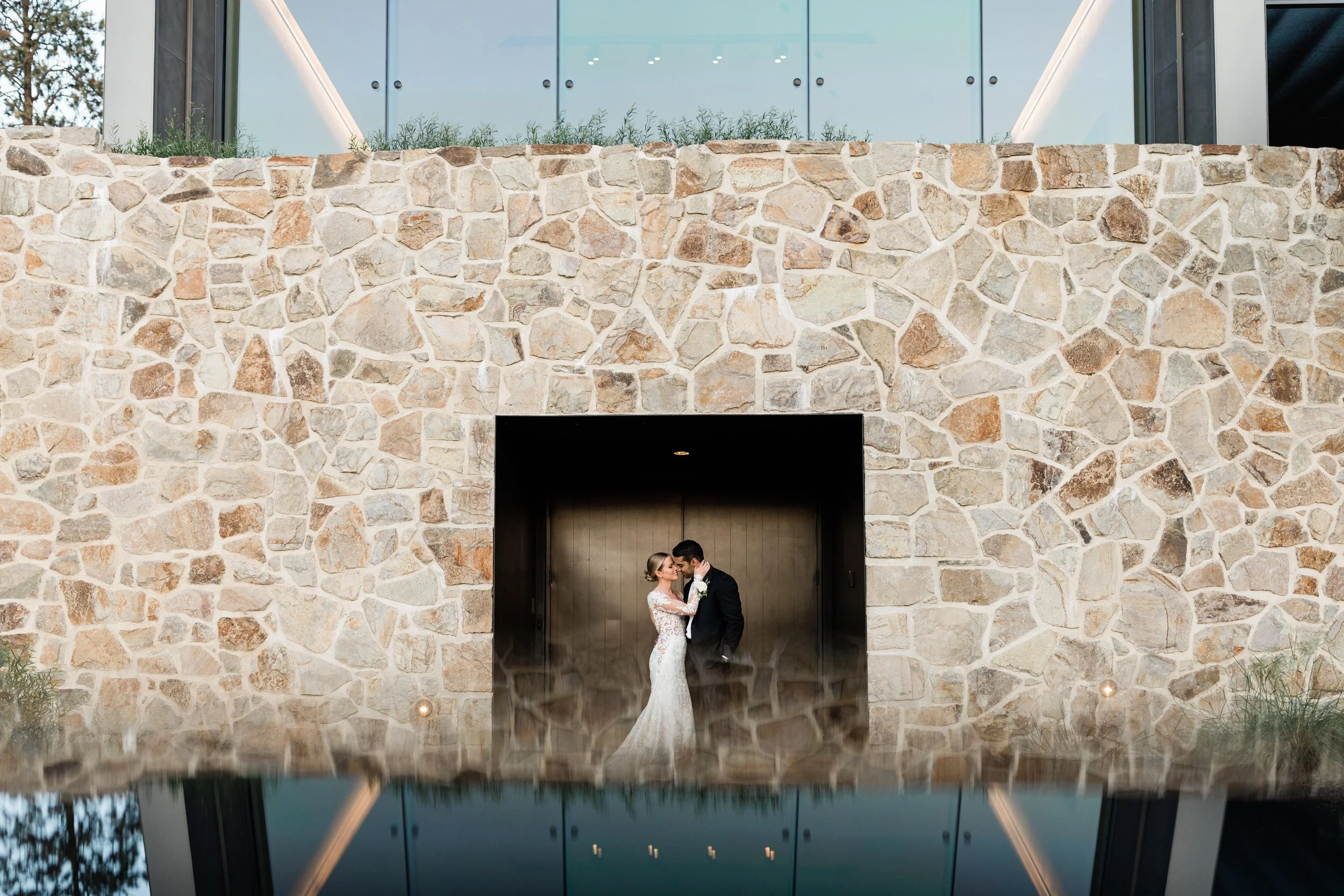 A bride and groom sharing a kiss in an open doorway against a stone wall exterior of a building.
Cedar Creek Estate Winery Wedding by Day by Knight Events
Photographer: royce sihlis photography