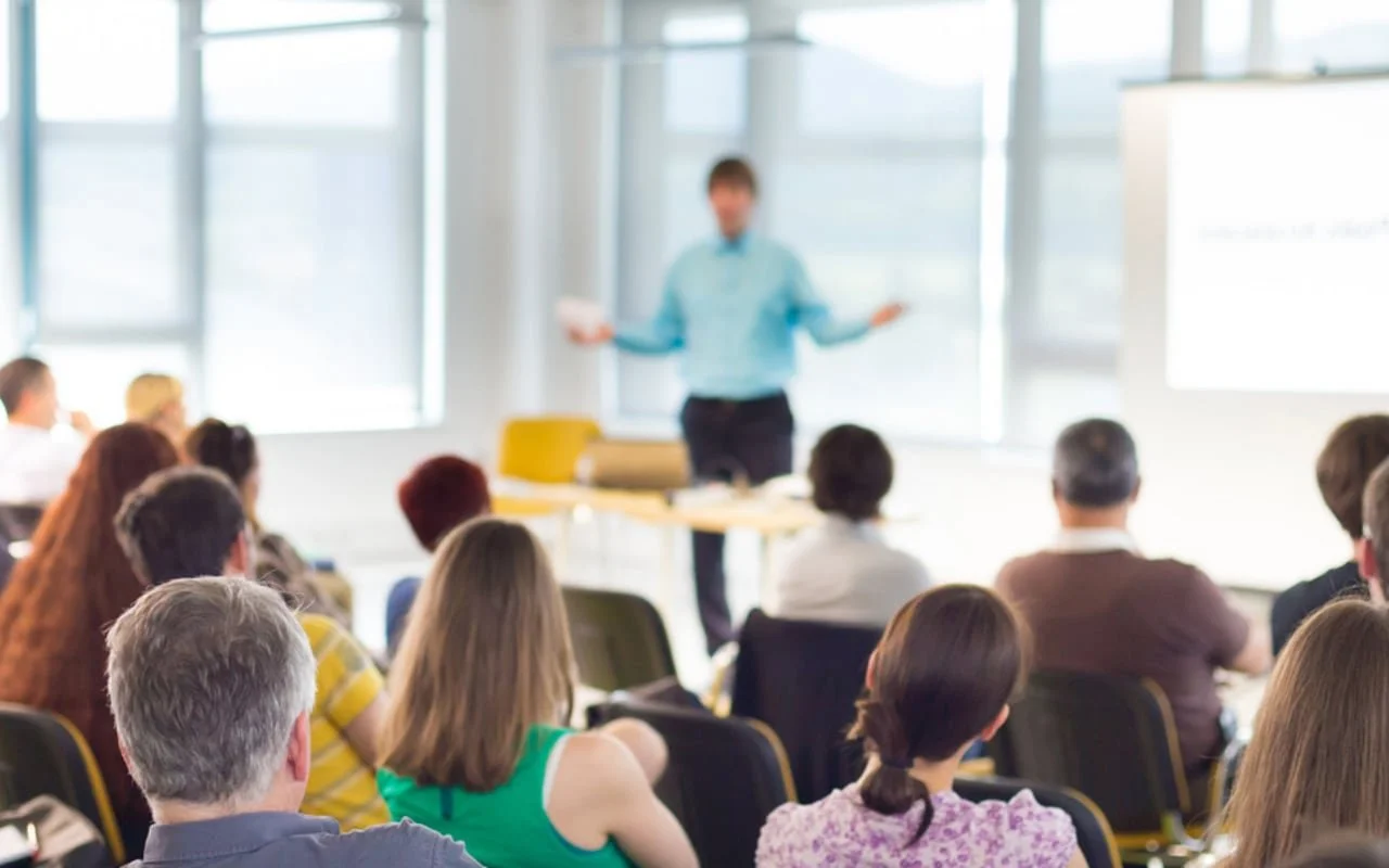 Group of people attending a presentation; speaker at the front.