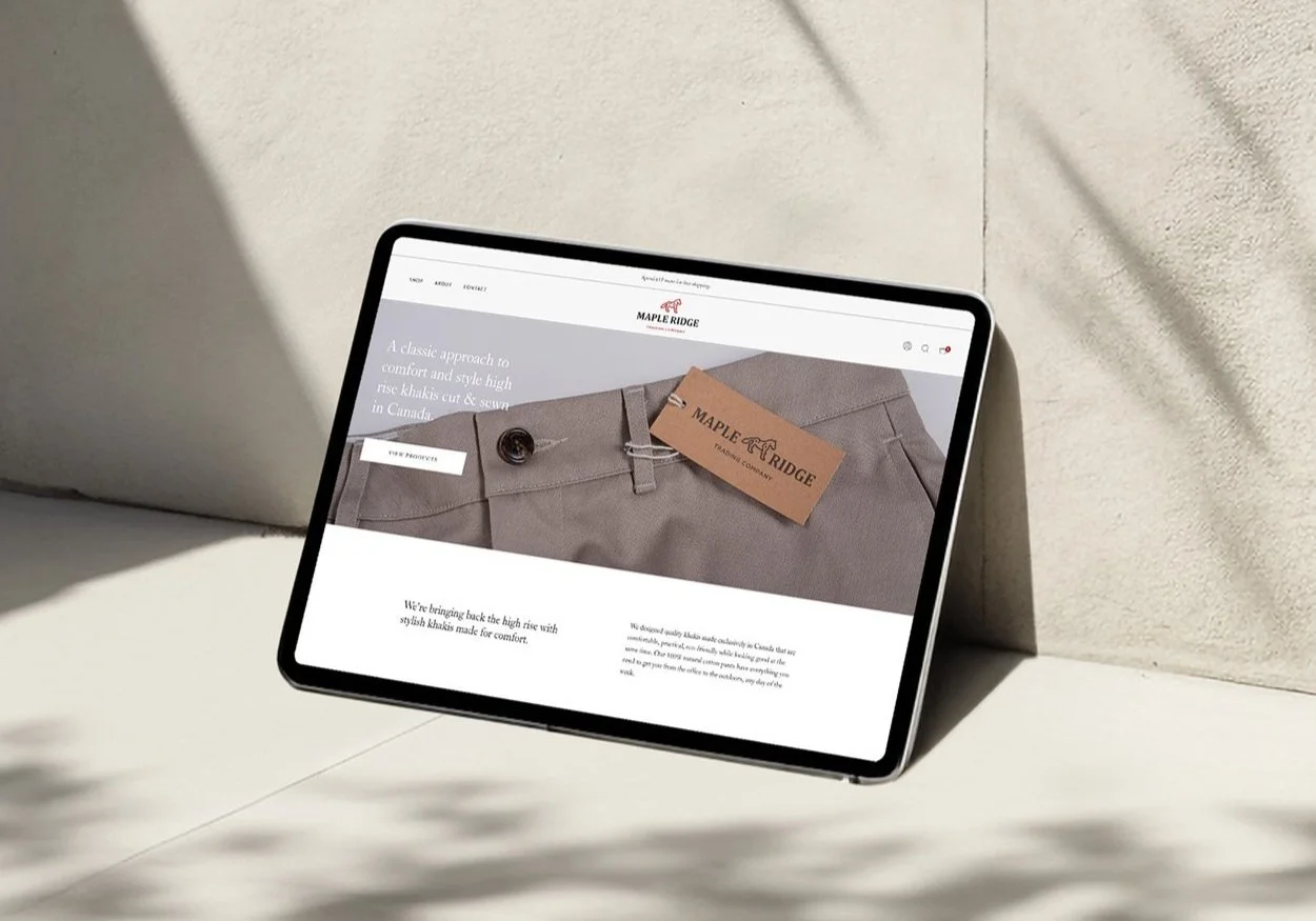 A tablet leaning against a wall with shadows, displaying a men's clothing online store