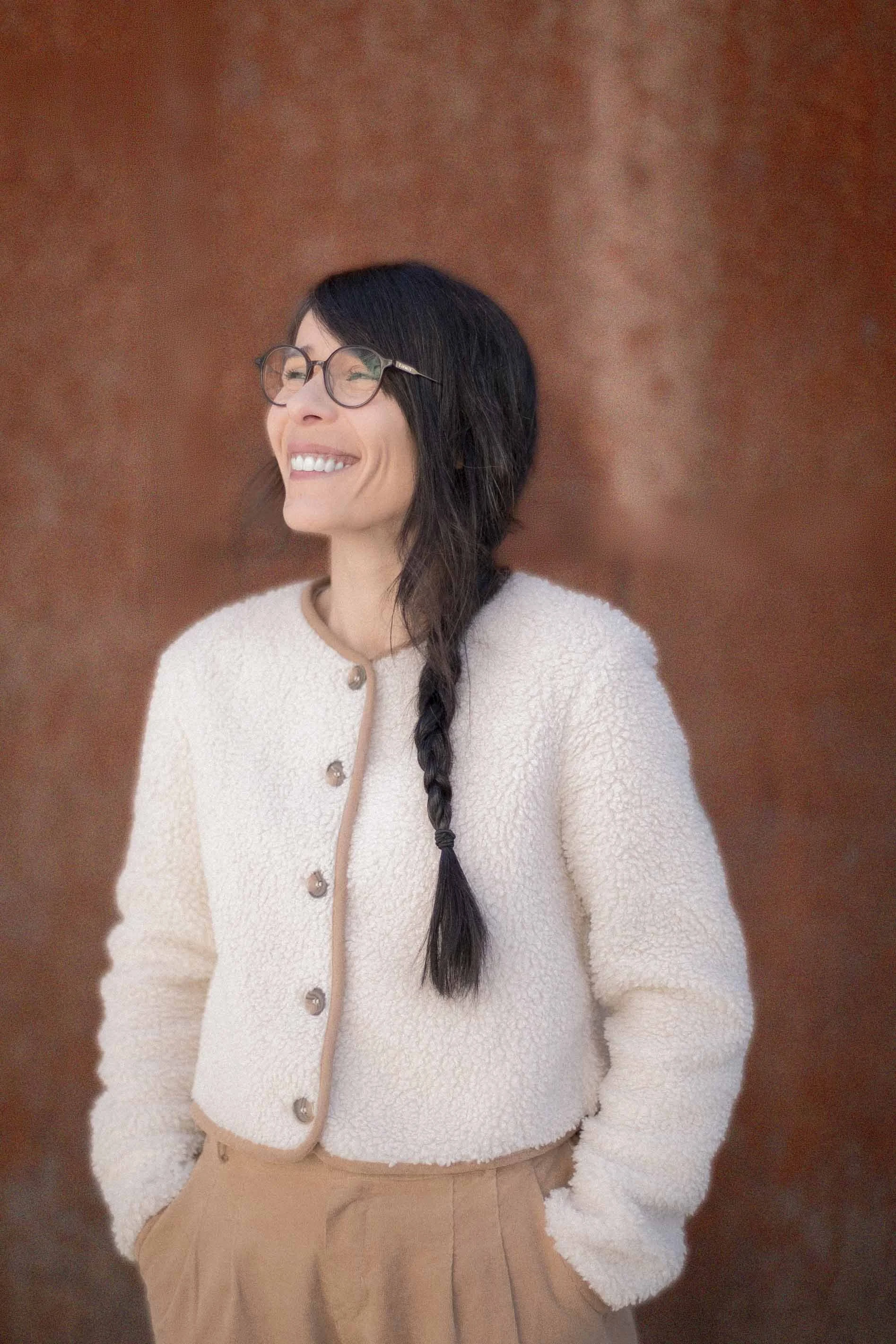 Squarespace web designer, Audrey Thizy, standing against a brown wall.