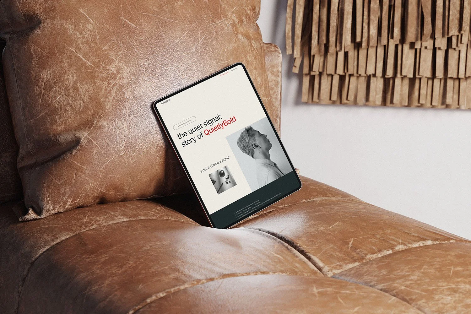 A tablet on a leather couch showcasing web design for small businesses, featuring a minimalist website titled “The Quiet Signal: Story of QuietlyBold.”