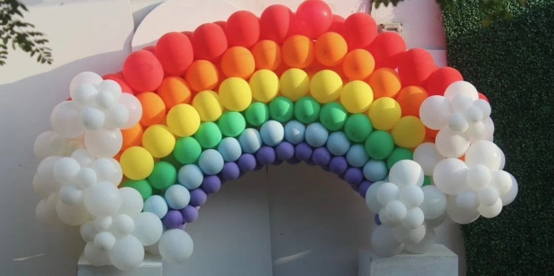 Rainbow made of colorful balloons, with white cloud balloons at both ends.