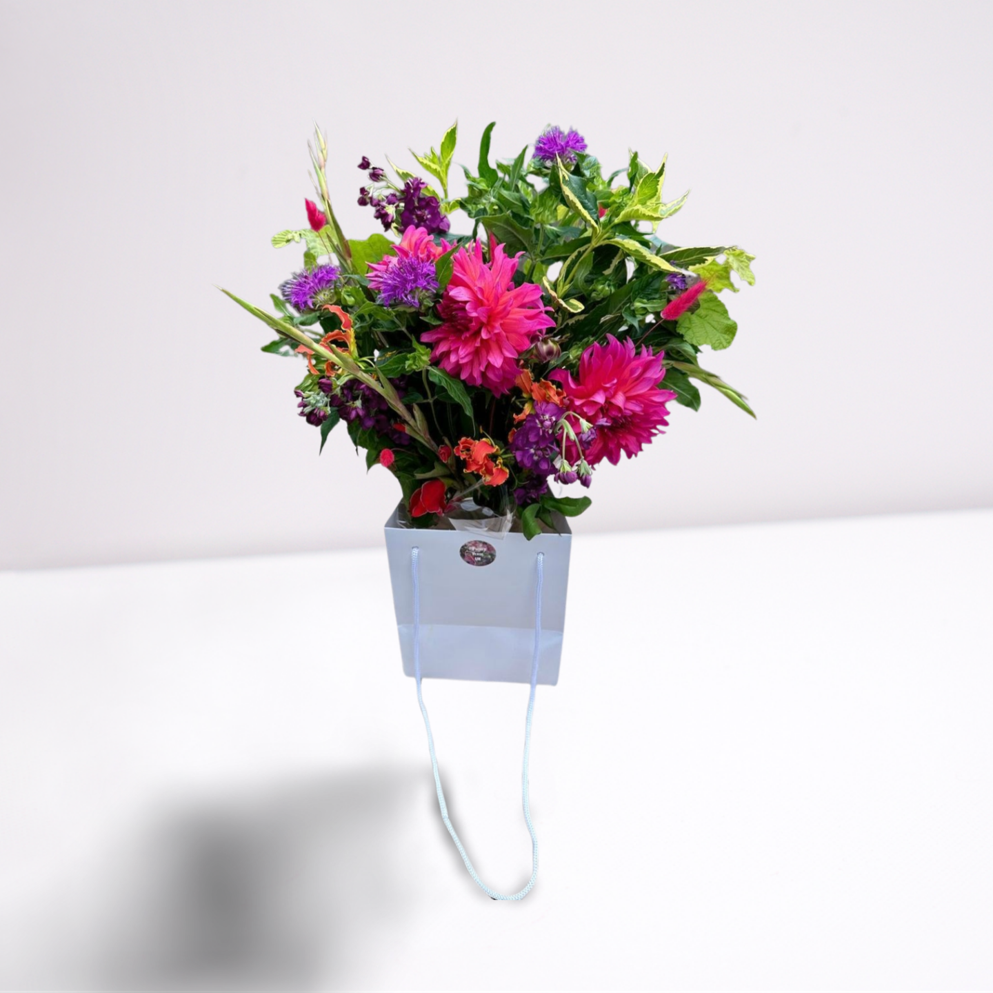 The Magdalene bouquet bouquet bursting with pink and purple flowers arranged in a decorative box
