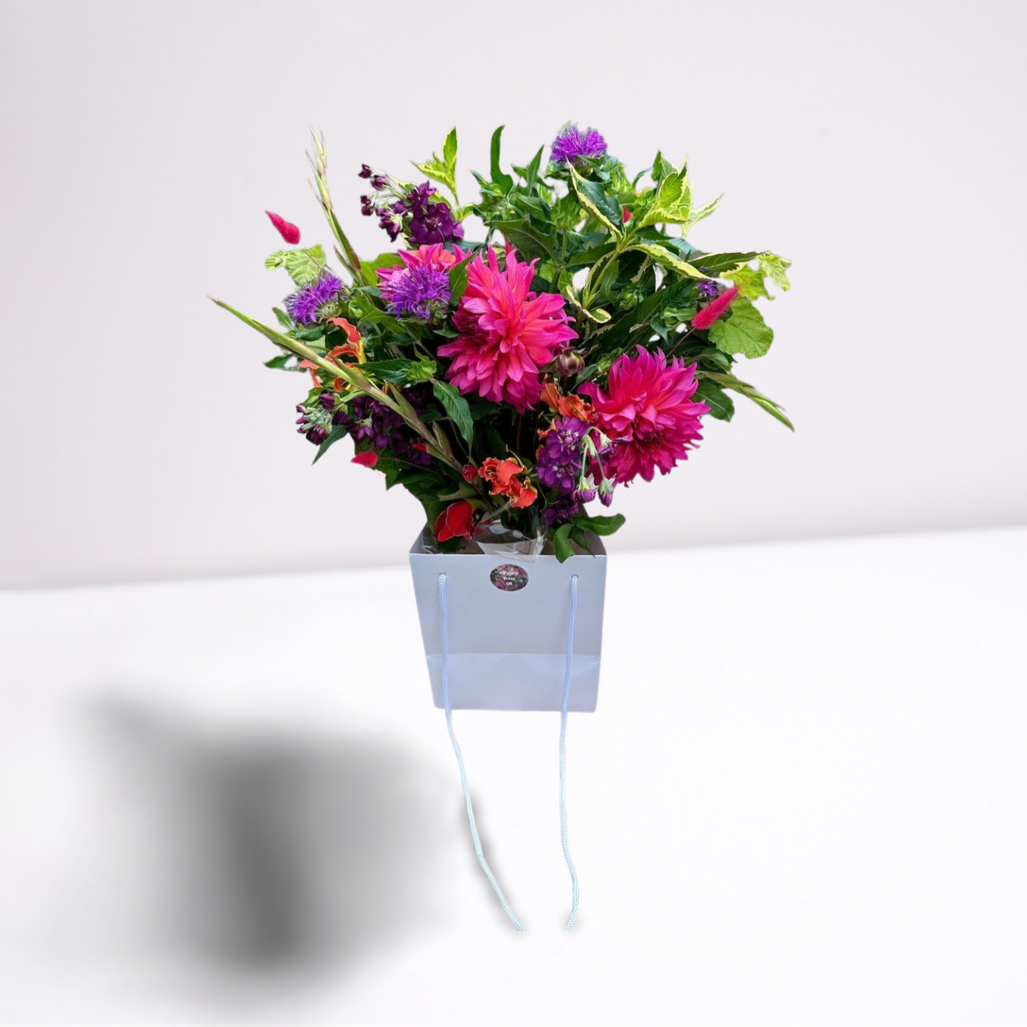 The Magdalene bouquet bouquet bursting with pink and purple flowers by Flowerverse of Cambridge