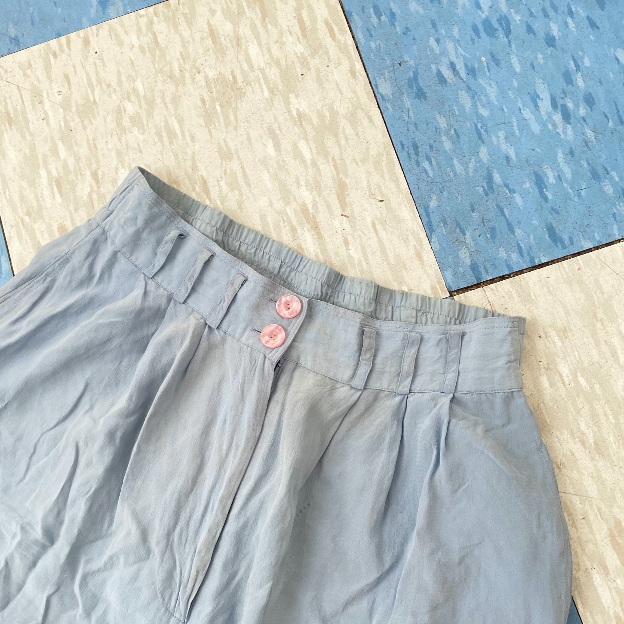 detail shot of blue silk trousers with pink pearlized buttons