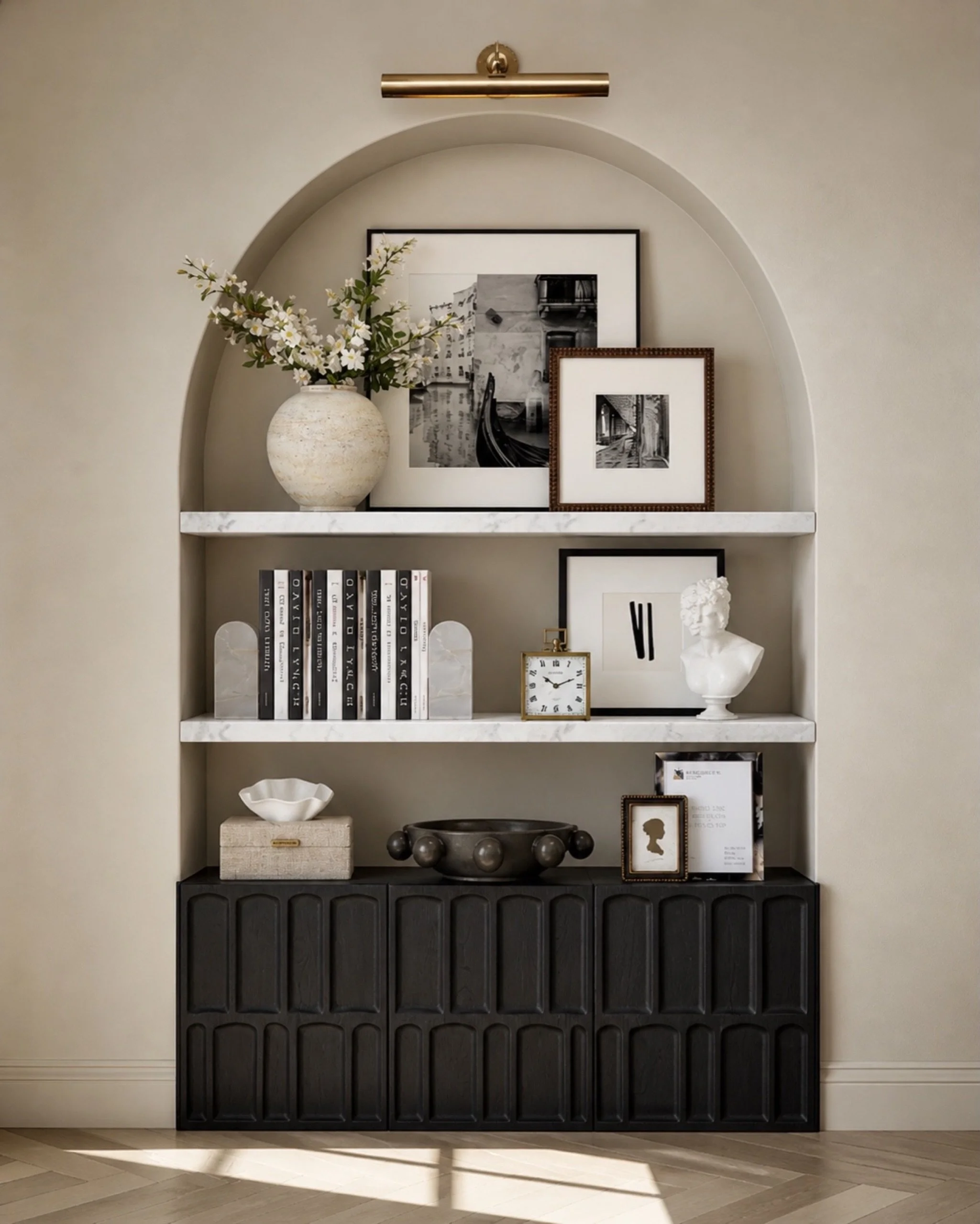 This is such an easy way to make a blank wall feel finished and intentional. A dark cabinet adds hidden storage, marble shelves keep it polished, and simple styling pieces like framed art, books, a vase, and a picture light make the whole space feel 