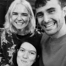 Three people smiling for a photo, two women and one man, in black and white.