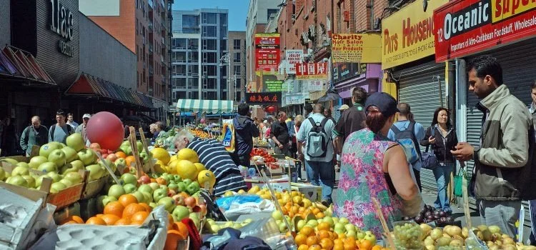 Street market with produce and people shopping on a busy city street