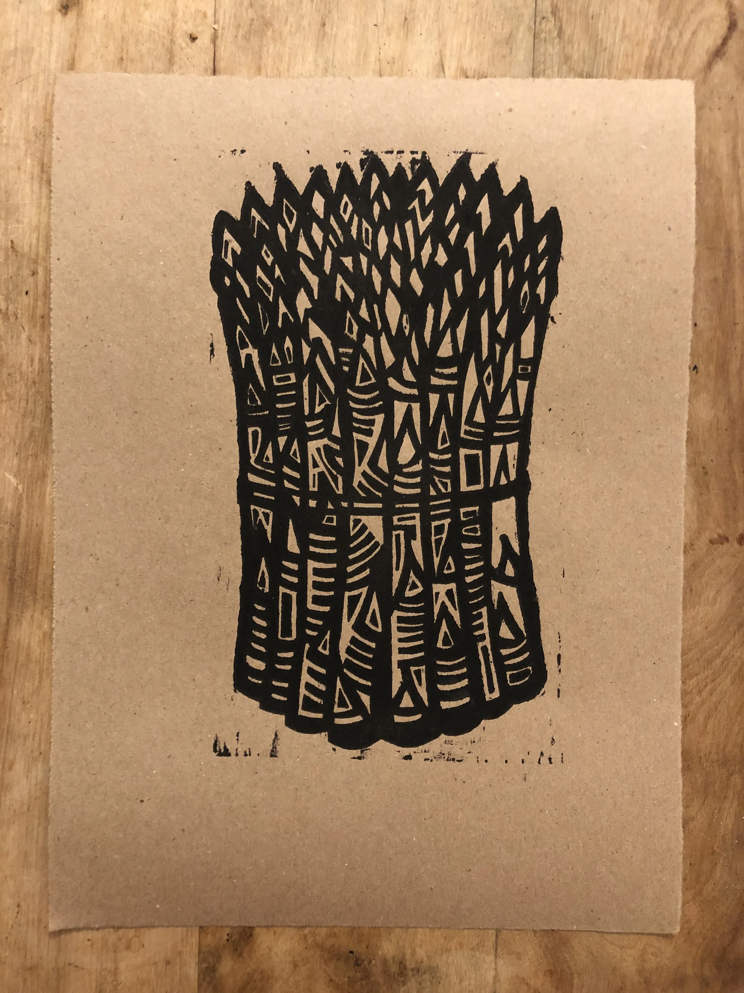 woodcut print of asparagus in black on brown craft paper