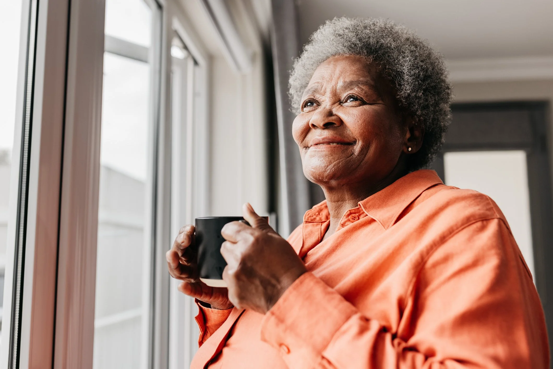 Thoughtful older woman looking out a window, symbolizing hope and life transitions