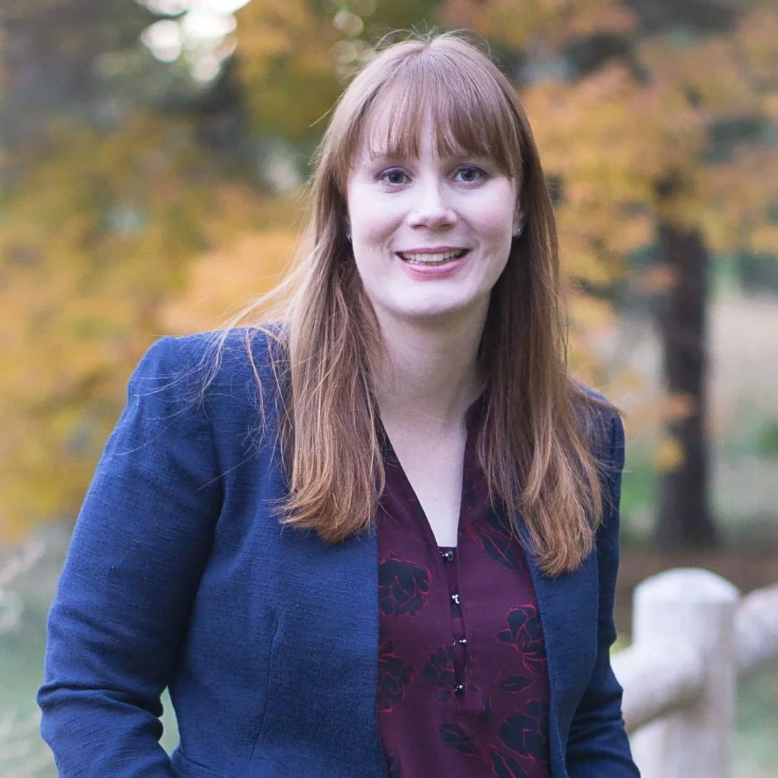 Smiling therapist standing outdoors by a wooden bridge, offering compassionate counseling and therapy for adults and older adults.